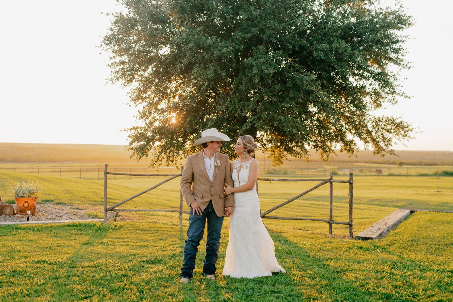 A couple poses against a sunset backdrop on their rustic ranch wedding day.