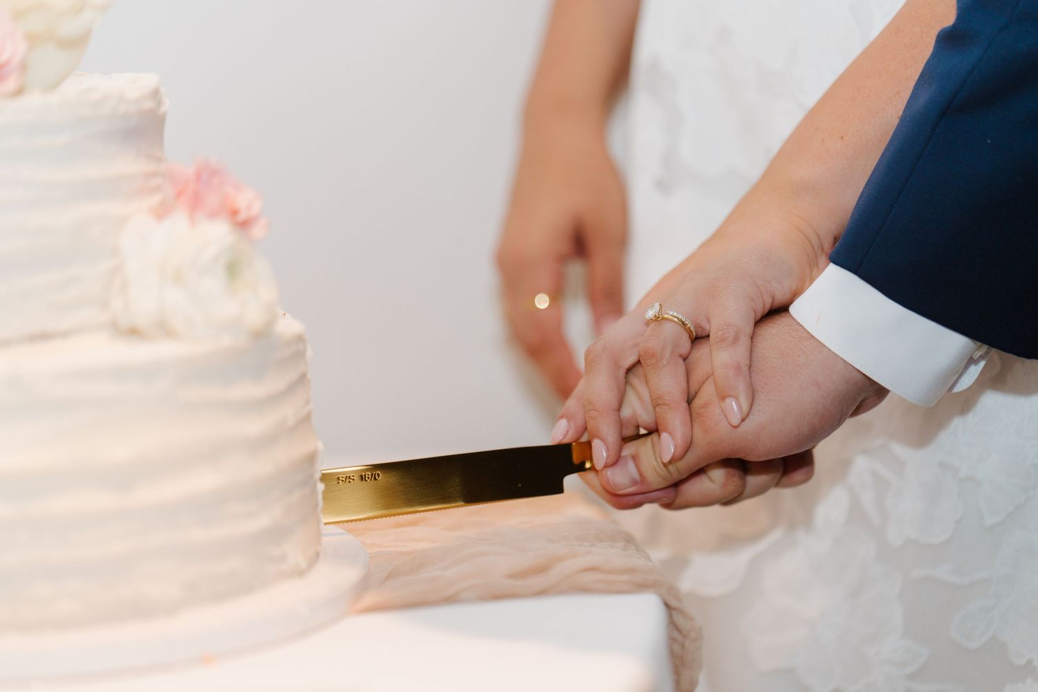 Close-up shots of hands cutting into a white wedding cake.