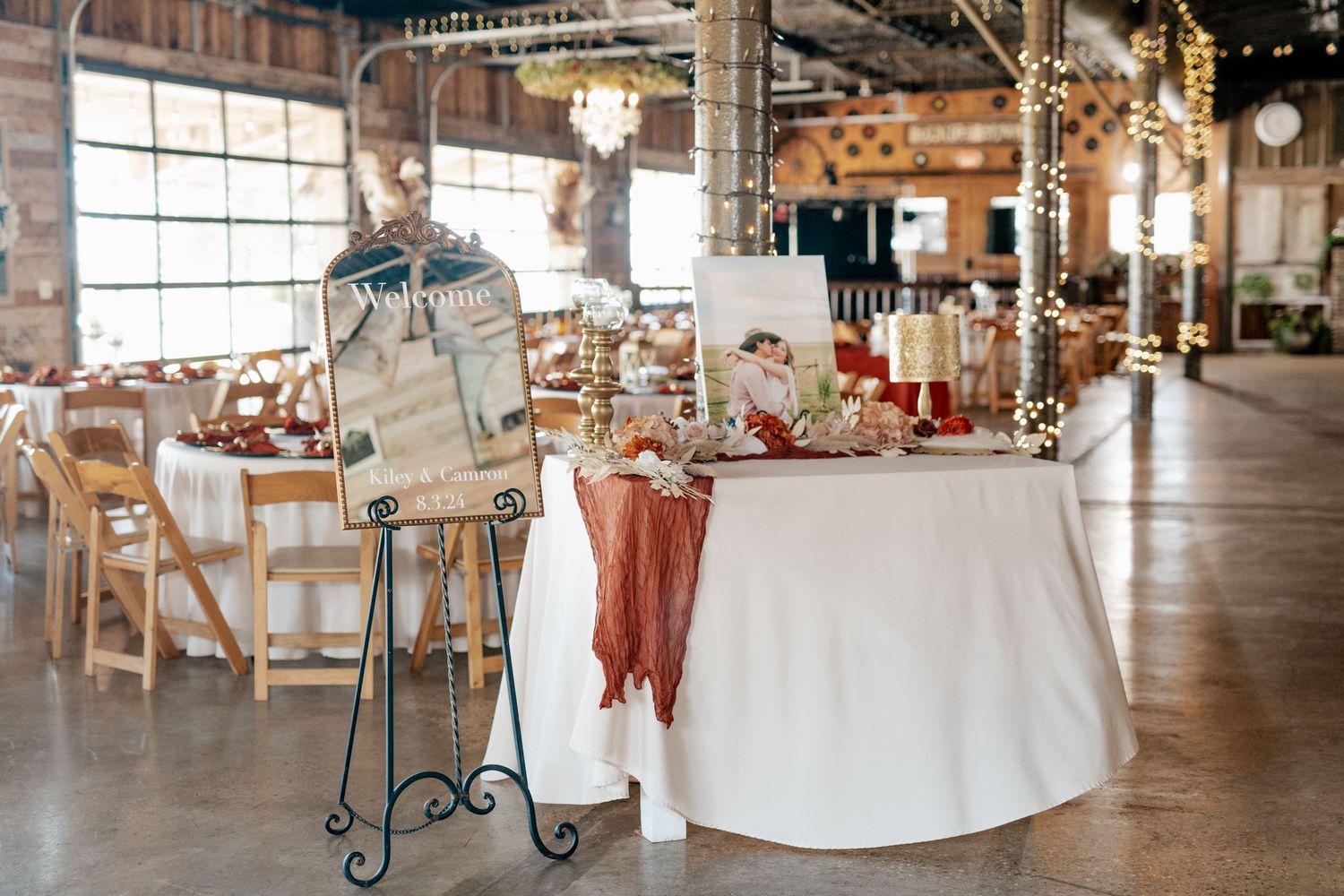 A rustic industrial event space with elegant table settings and decorative signage stand for a wedding reception.