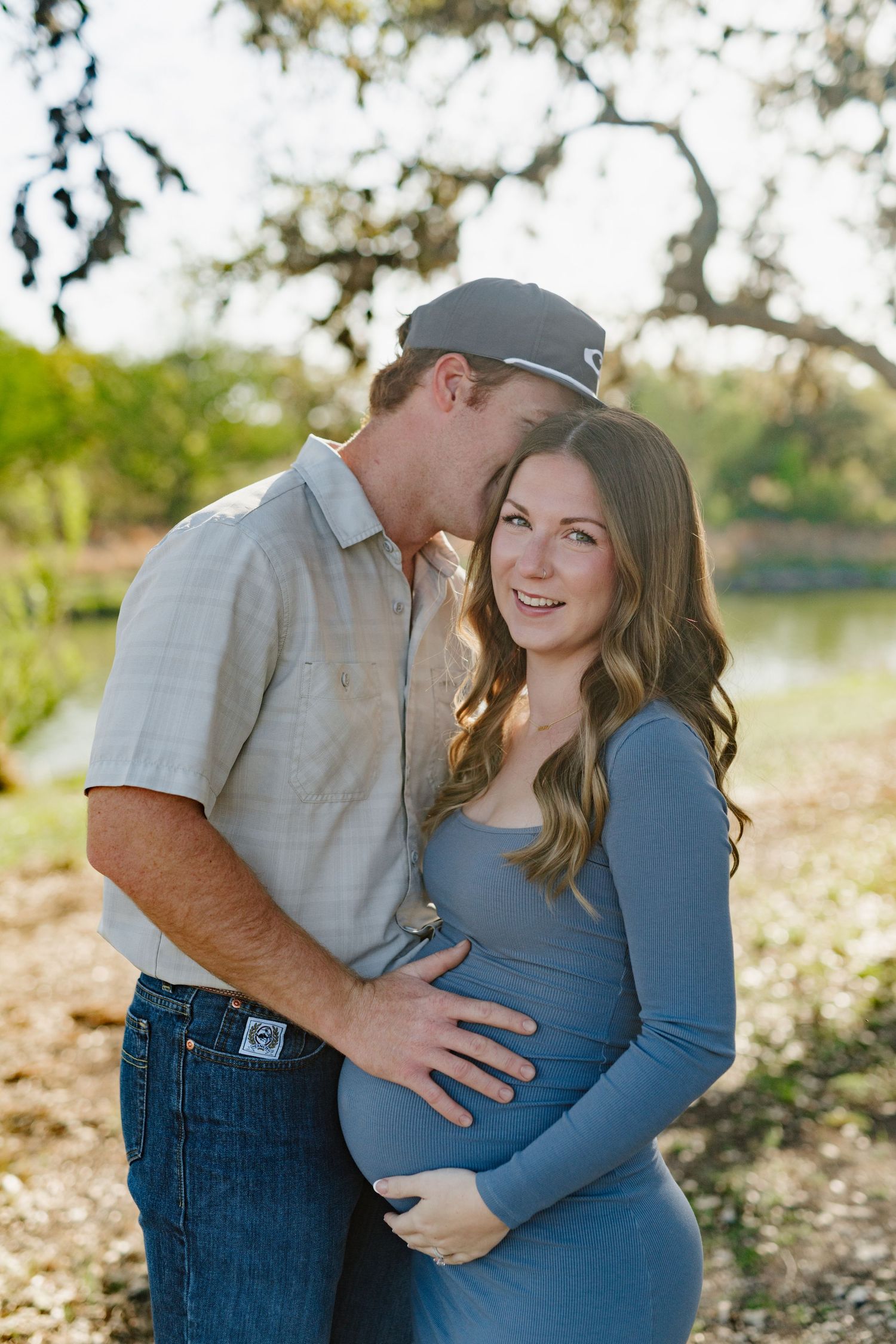 Intimate maternity portrait showcasing a tender moment beside a lakeside setting.