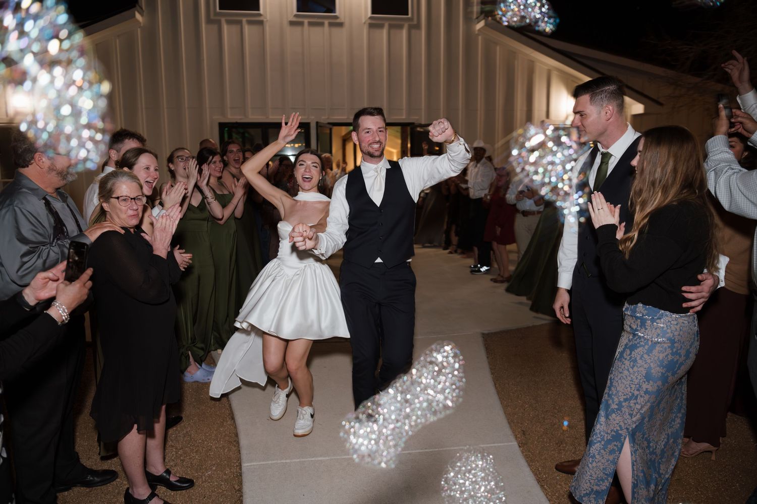 Wedding reception dance floor filled with guests celebrating and dancing under sparkly lighting.