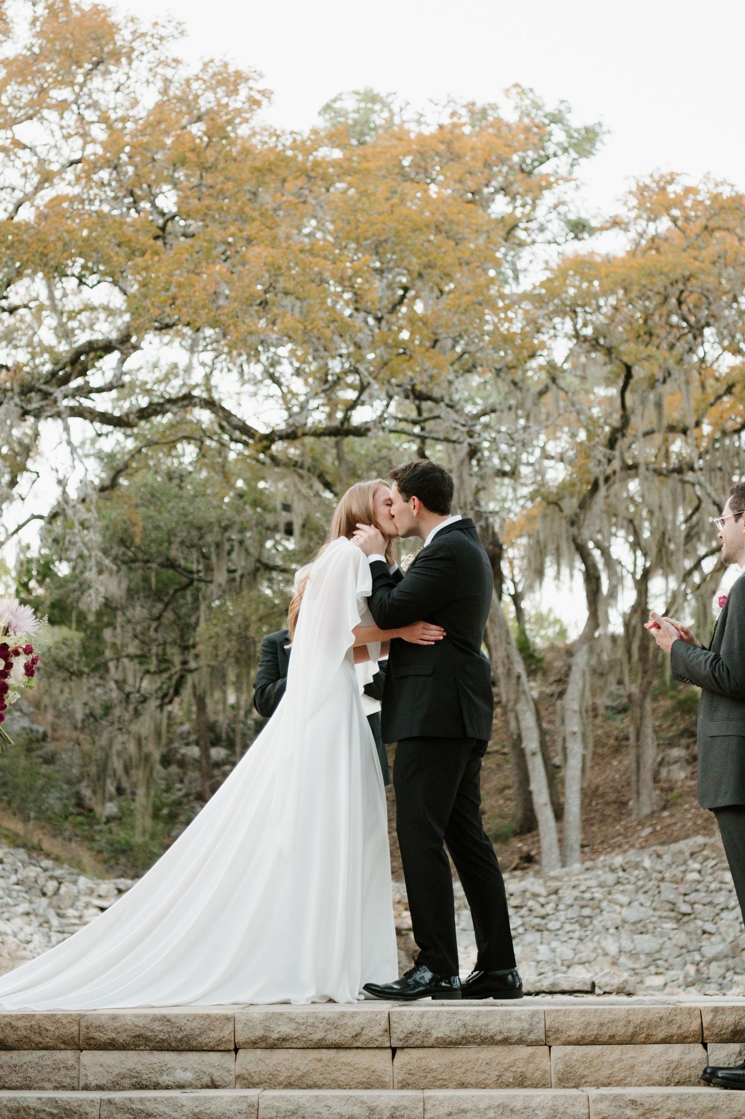 Wedding ceremony takes place under autumn trees with Spanish moss.