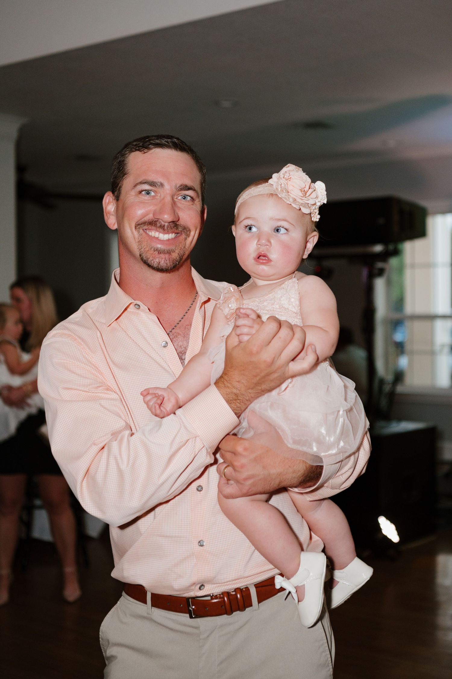 Sweet moment between a person wearing pink holding a baby dressed in white.