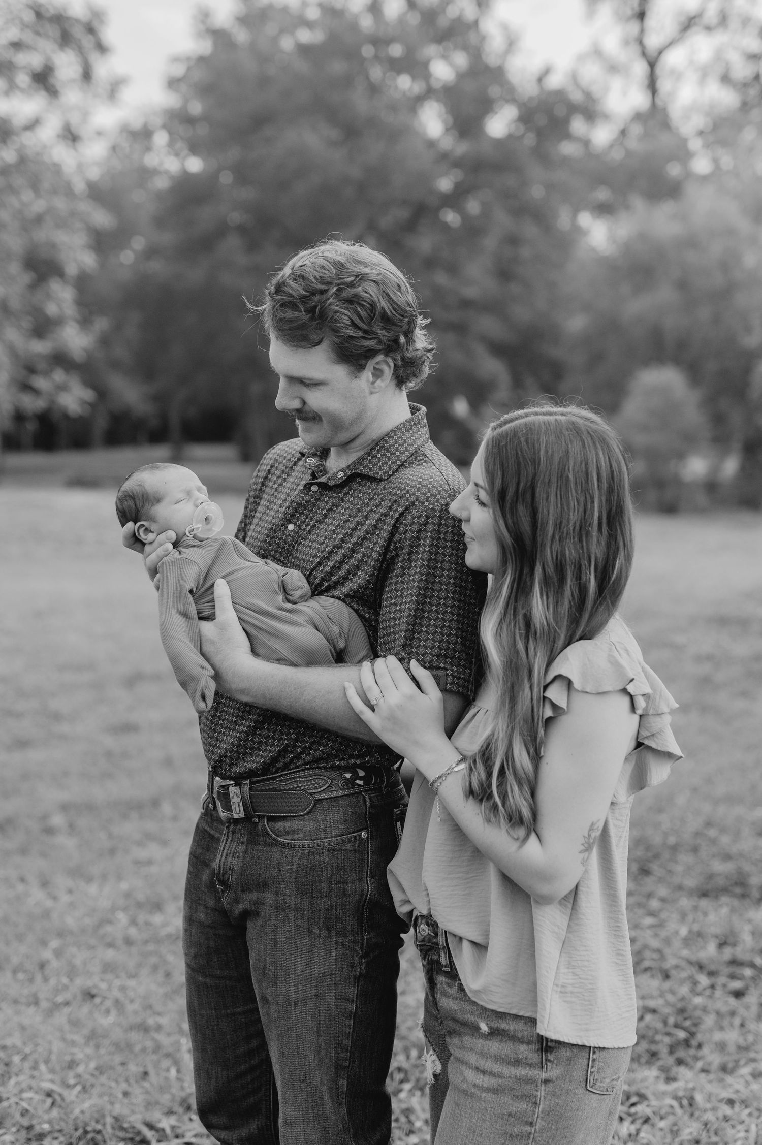 Black and white series of intimate family portraits taken outdoors showing tender moments between loved ones.
