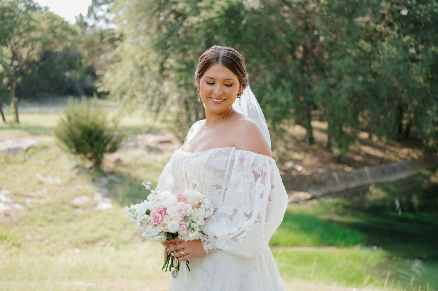 Elegant bridal portraits featuring a white lace gown and pink bouquet in a natural outdoor setting.