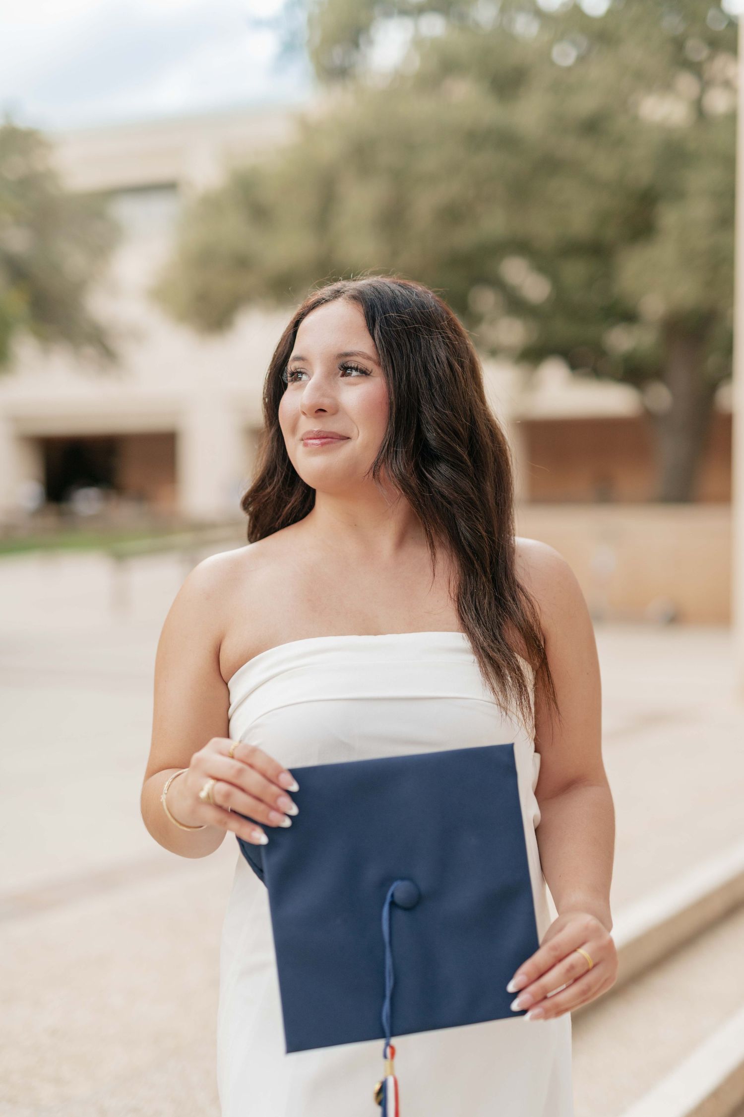Graduate holds blue diploma cover while wearing a white dress.