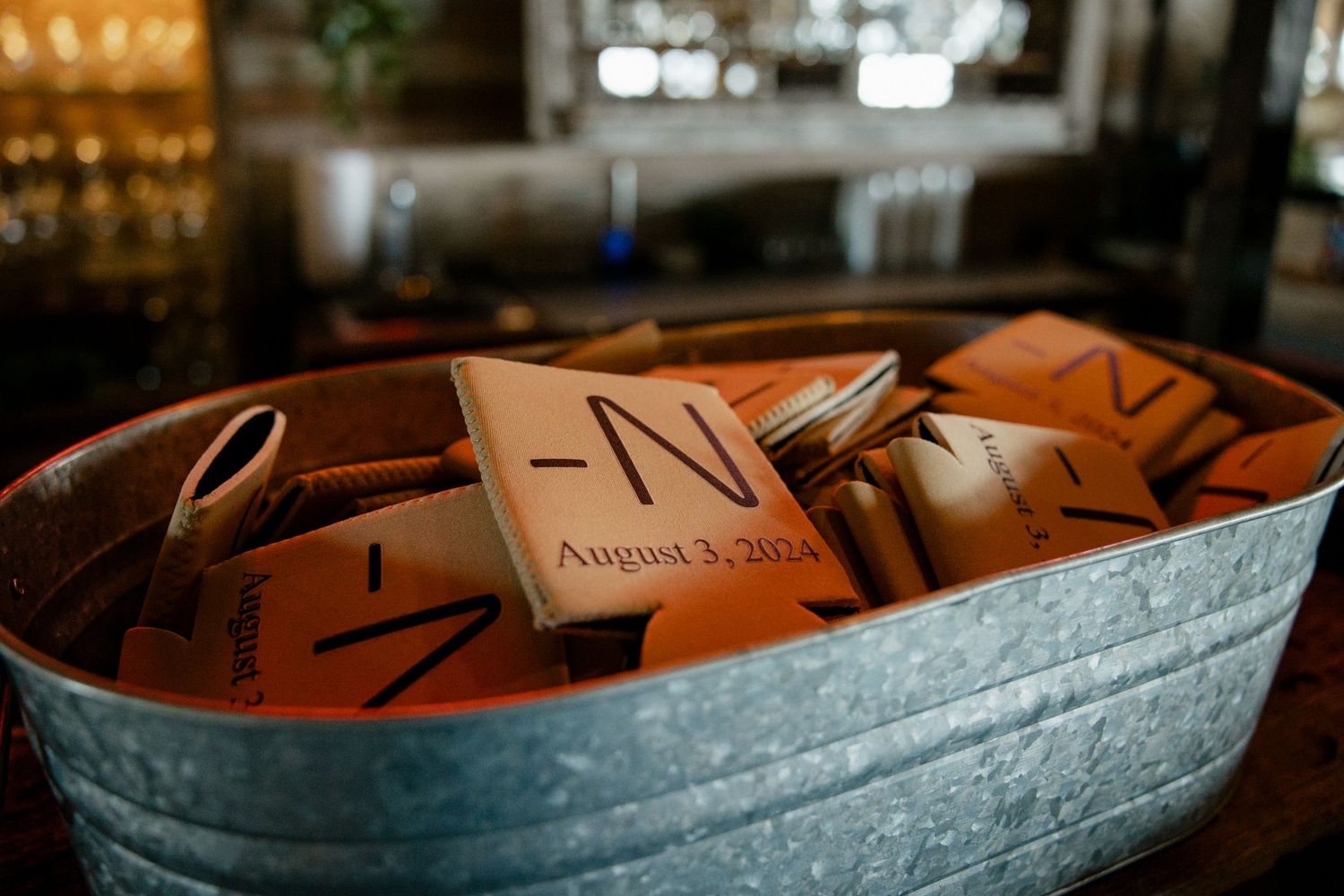 Rustic metal tub filled with brown paper wedding programs for guests at an event.