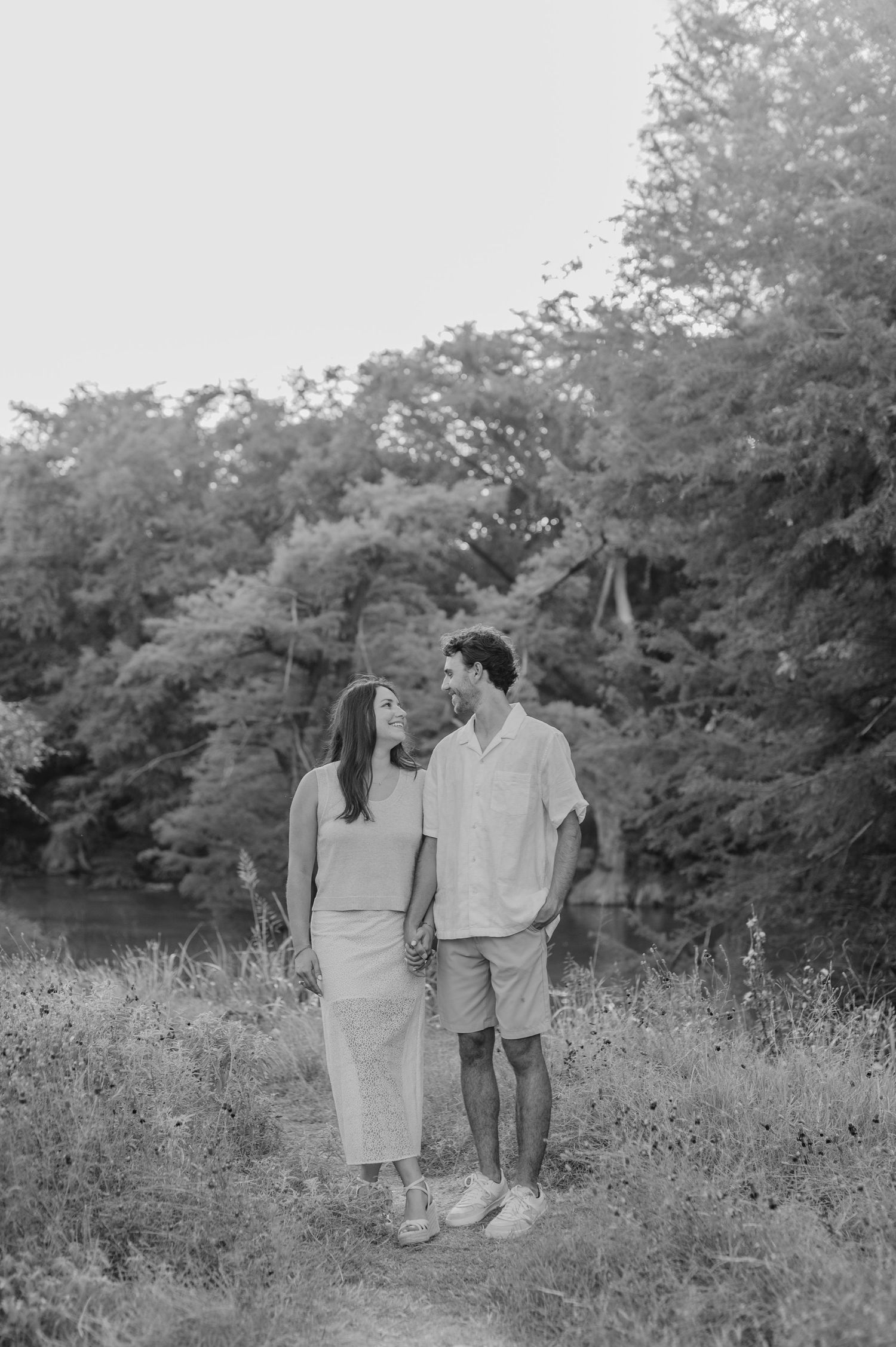 Black and white photo of a couple walking together through a wildflower meadow.