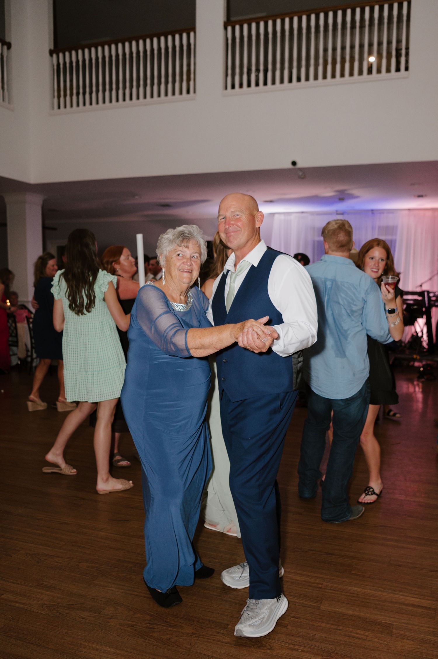 Couples dancing together on wooden dance floor at evening reception.