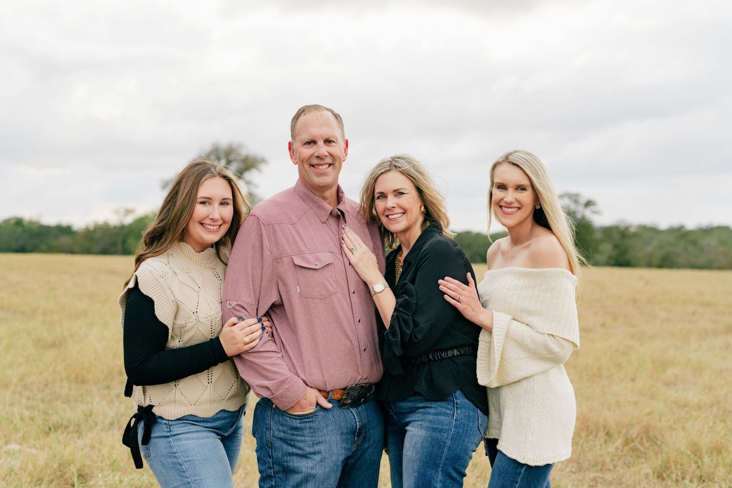 Family portrait in a golden field with matching casual outfits.