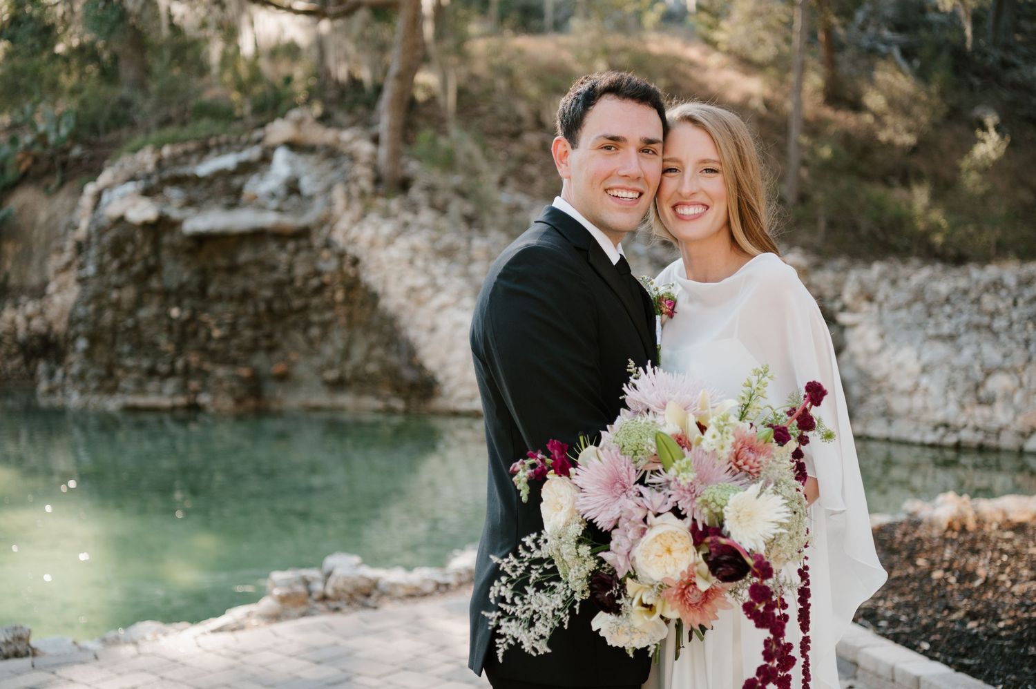 Outdoor wedding photography in a natural setting with a waterfall and rocky landscape backdrop.