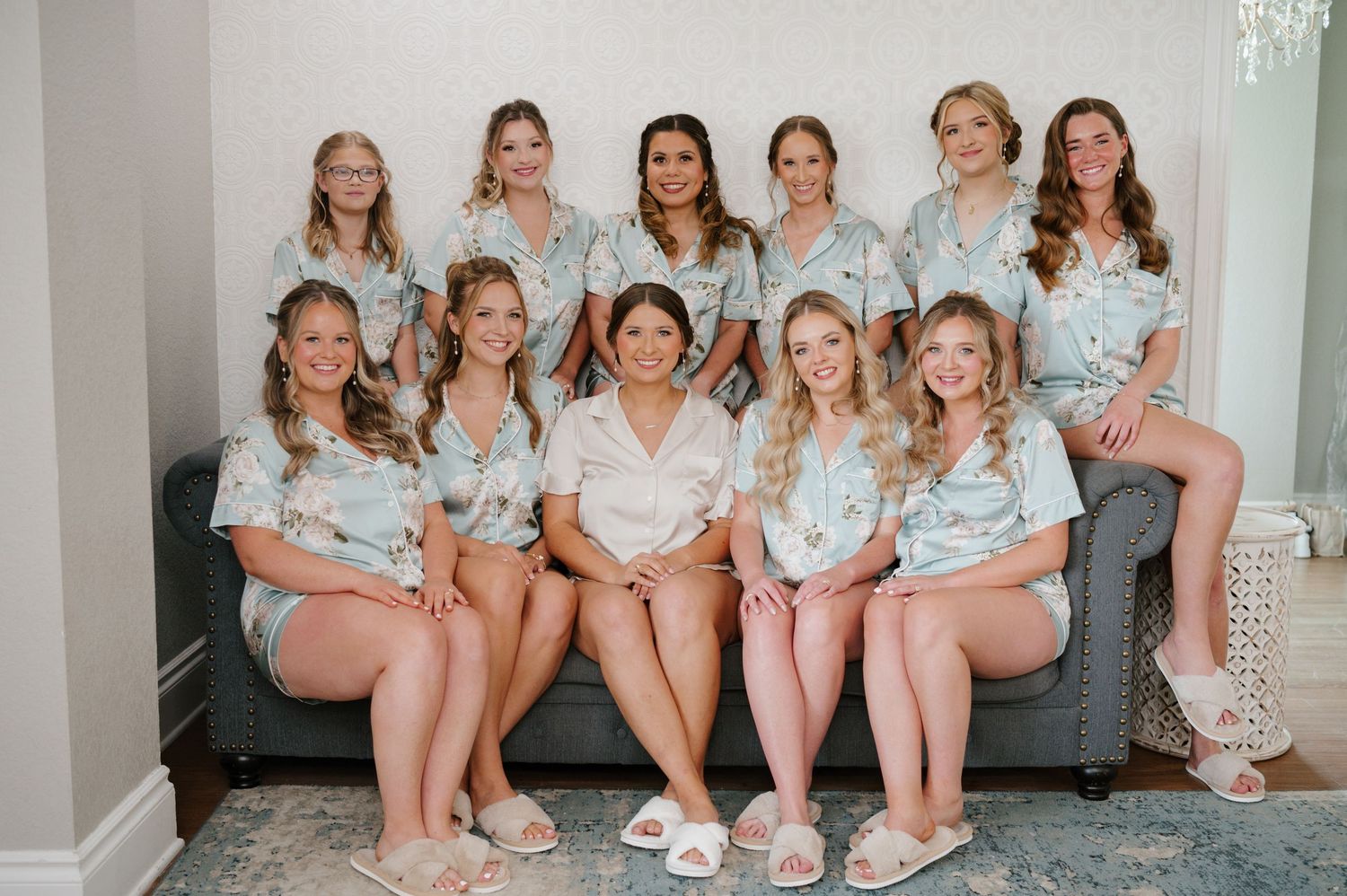 A group in matching floral robes sits together on a grey couch in a bright, minimalist room.