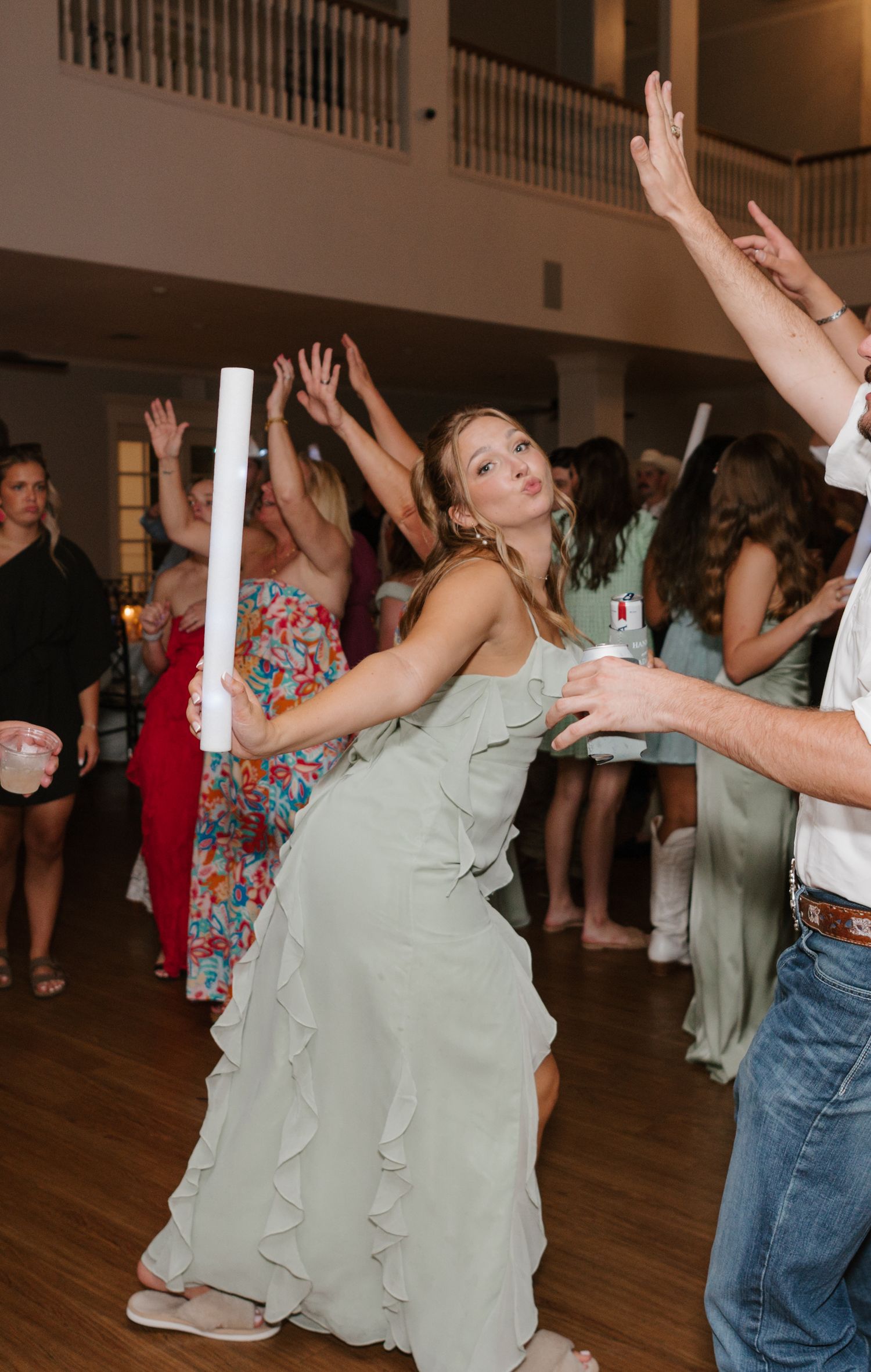 Party guests dancing enthusiastically on a wooden dance floor during a festive celebration.