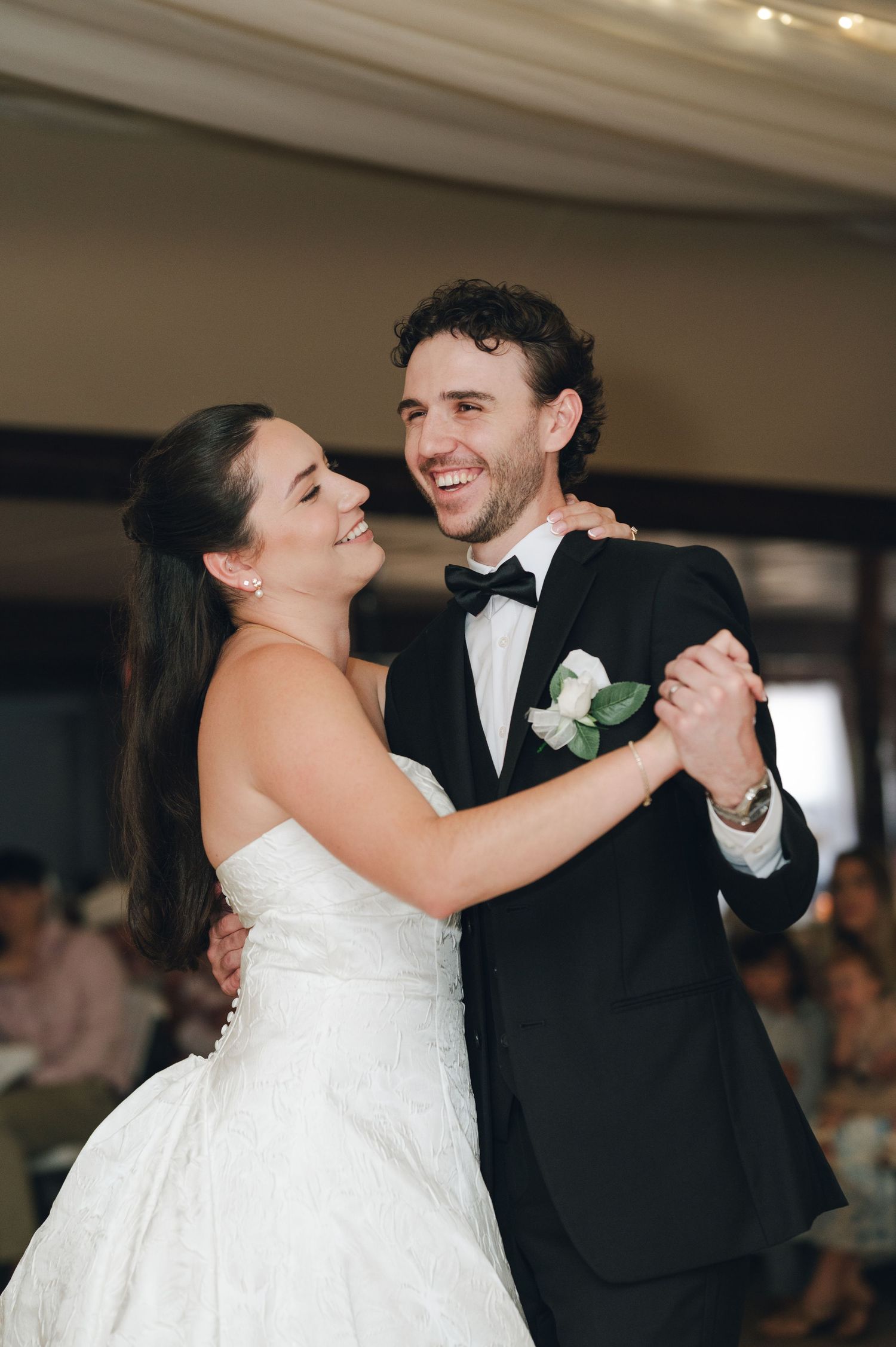 Bride and groom sharing a joyful first dance at their wedding reception in elegant formal attire.