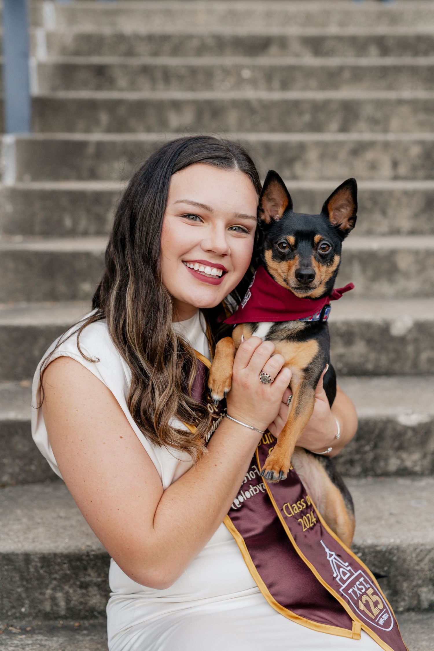 A girl's senior session at Texas State University posed with her dog on stairs.