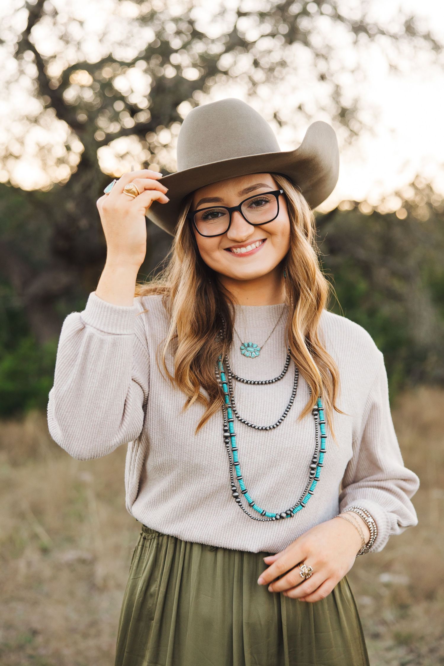 A western style portrait with turquoise jewelry and gray cowboy hat in a natural setting.
