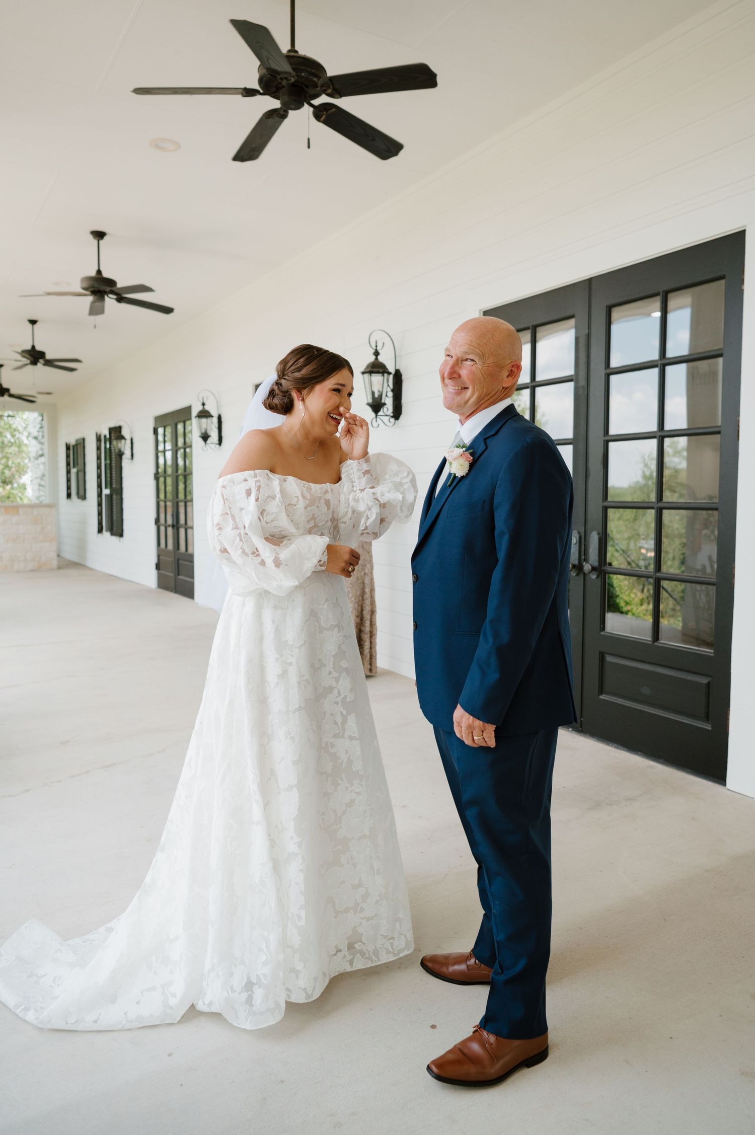 Wedding first look photos showing tender moments in a bright white covered porch with ceiling fans.
