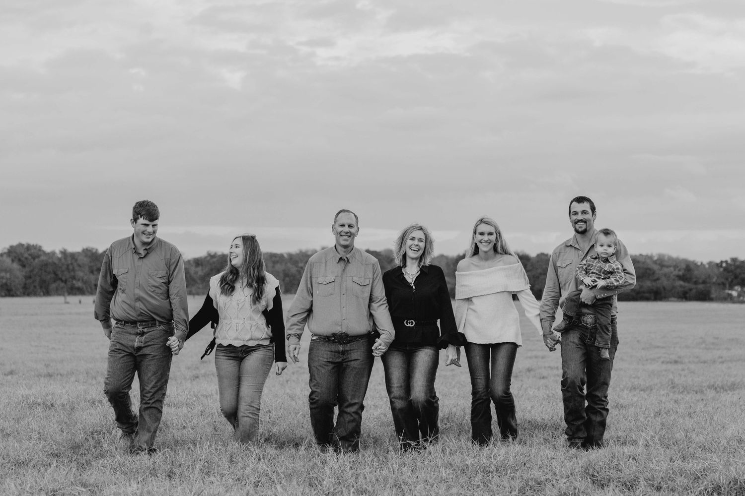 A black and white portrait of a family group standing together in a meadow.
