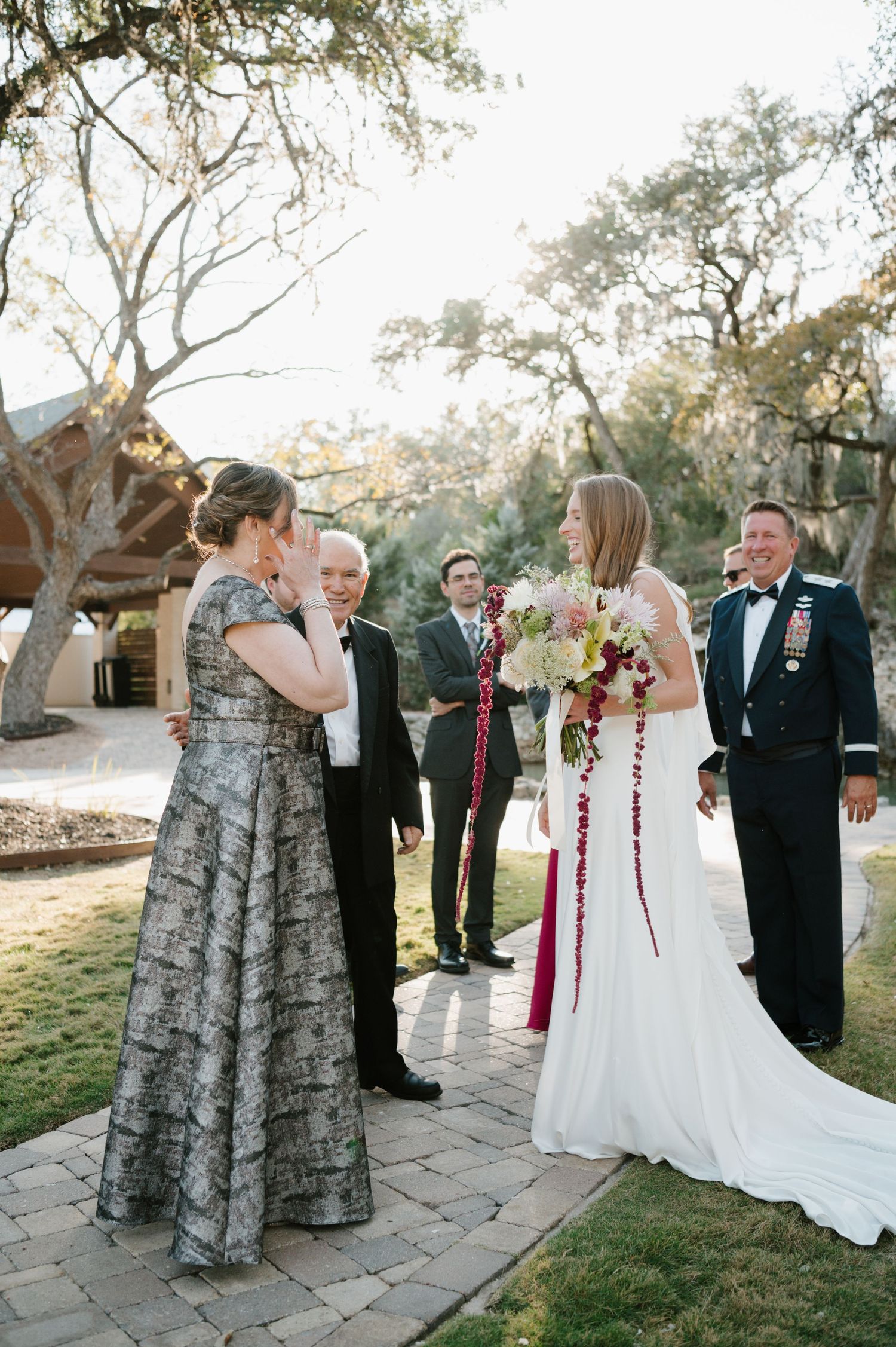 Wedding party gathers on stone patio during outdoor celebration.