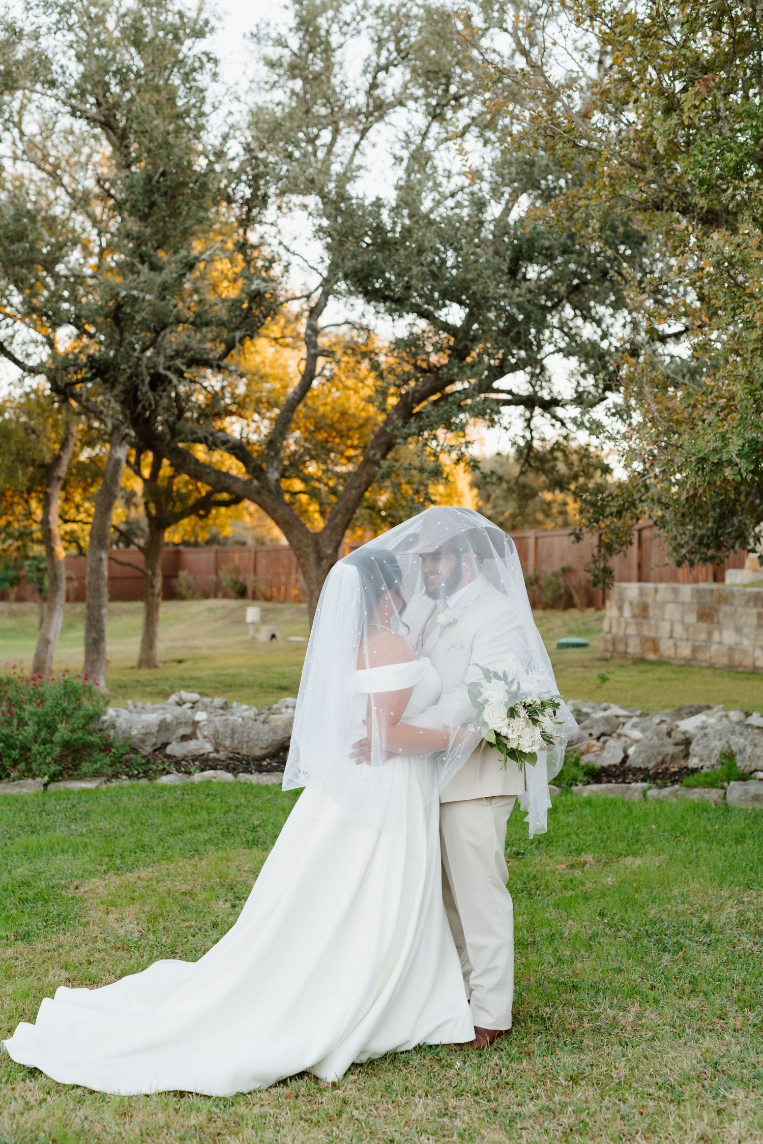A romantic outdoor wedding scene in autumn with a flowing white dress and veil against a backdrop of golden trees.
