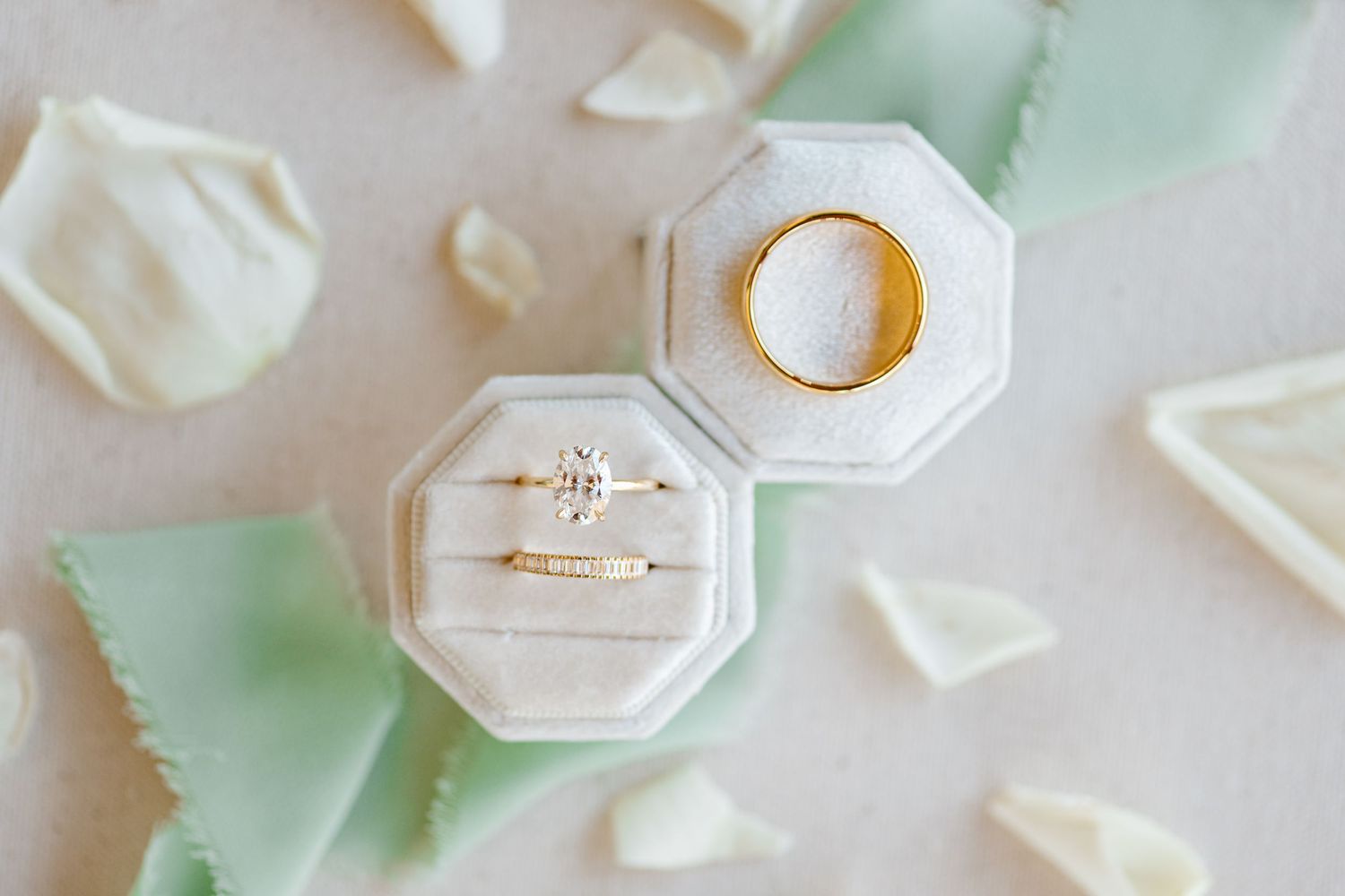 Two white octagonal ring boxes with delicate engagement rings on mint green and white background.