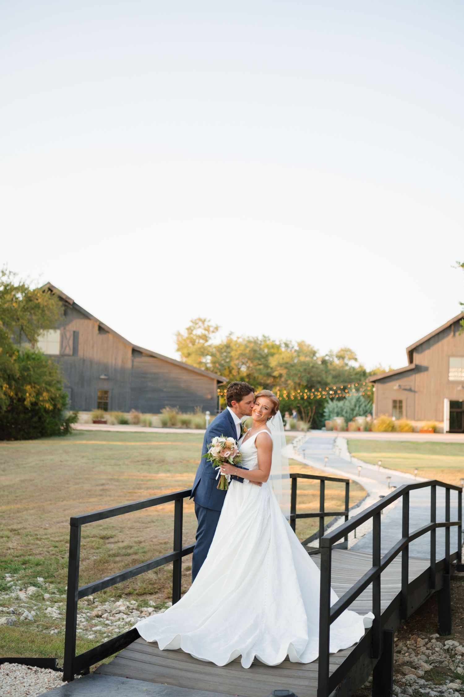 A couple shares romantic moments on a wooden bridge during a sunset photo session in a rustic outdoor setting.