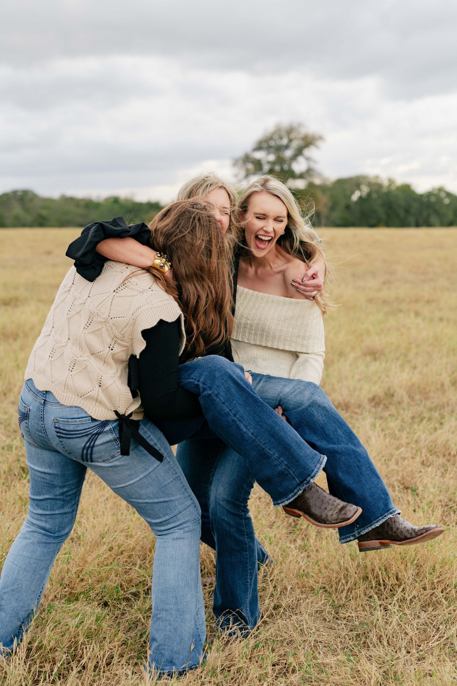 Candid shot of three people laughing and playing in a field.