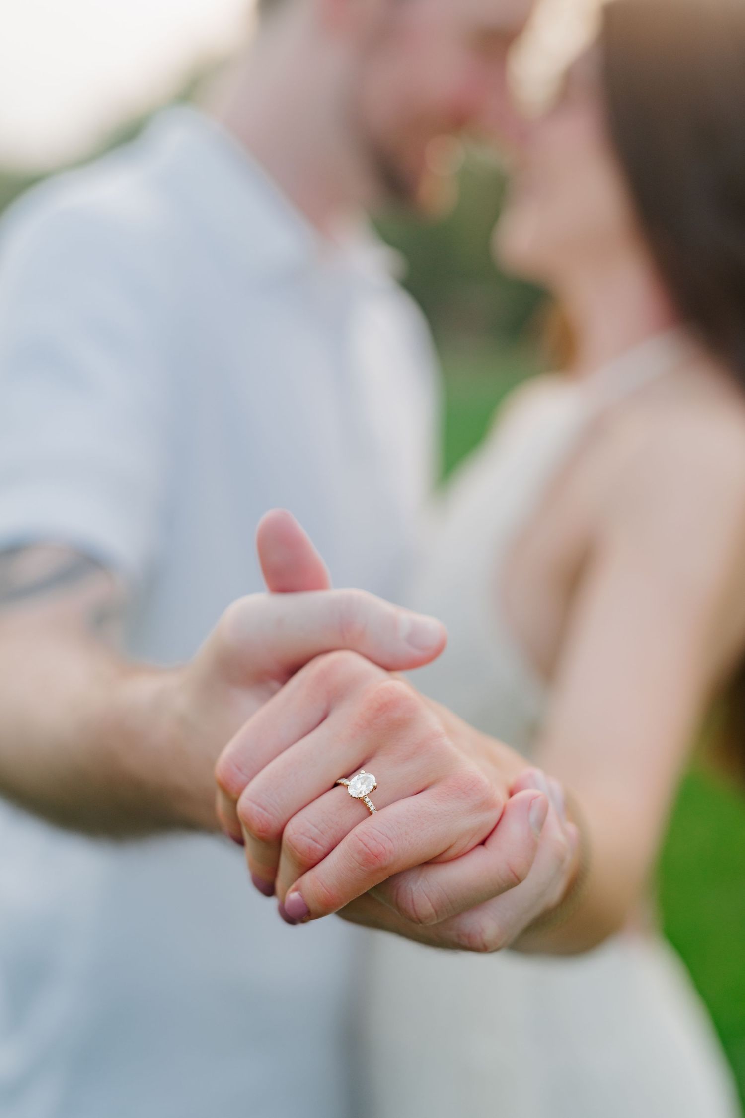 Close up of engagement ring as couple holds hands during outdoor photo session.