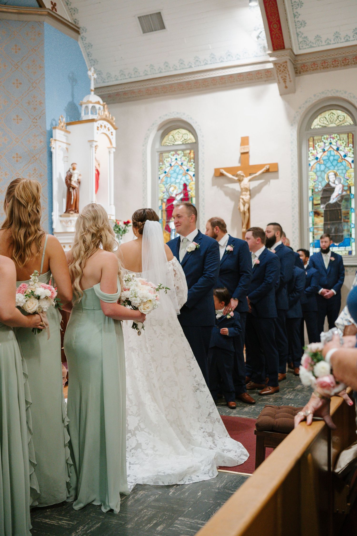 Traditional church wedding ceremony with wedding party in sage green and navy attire.