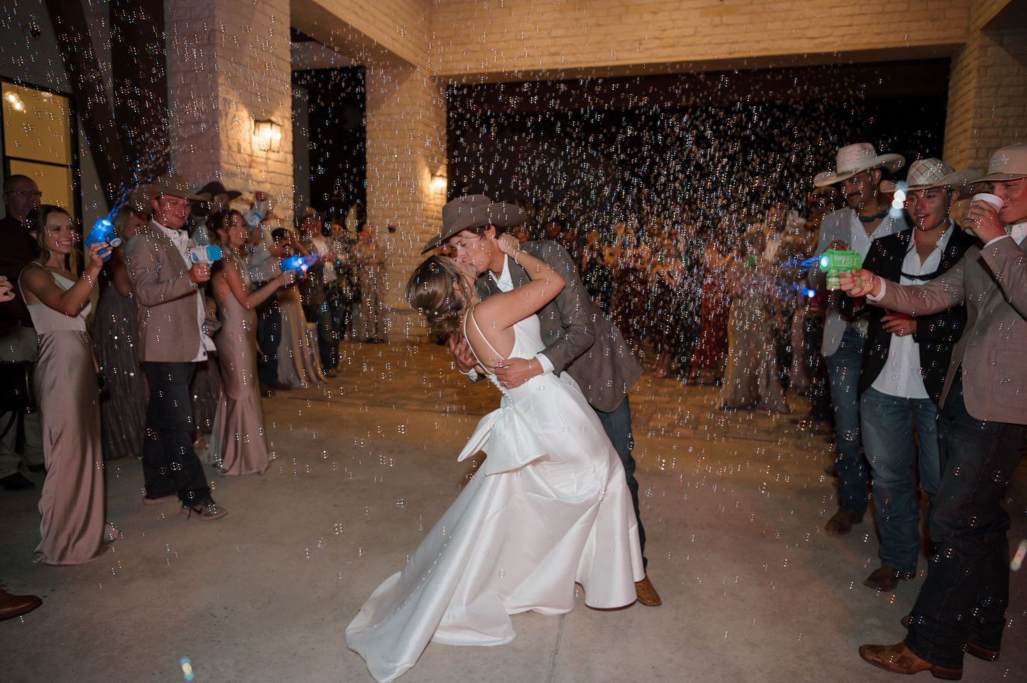 A couple shares their first dance while guests shower them with sparklers in an indoor reception venue.