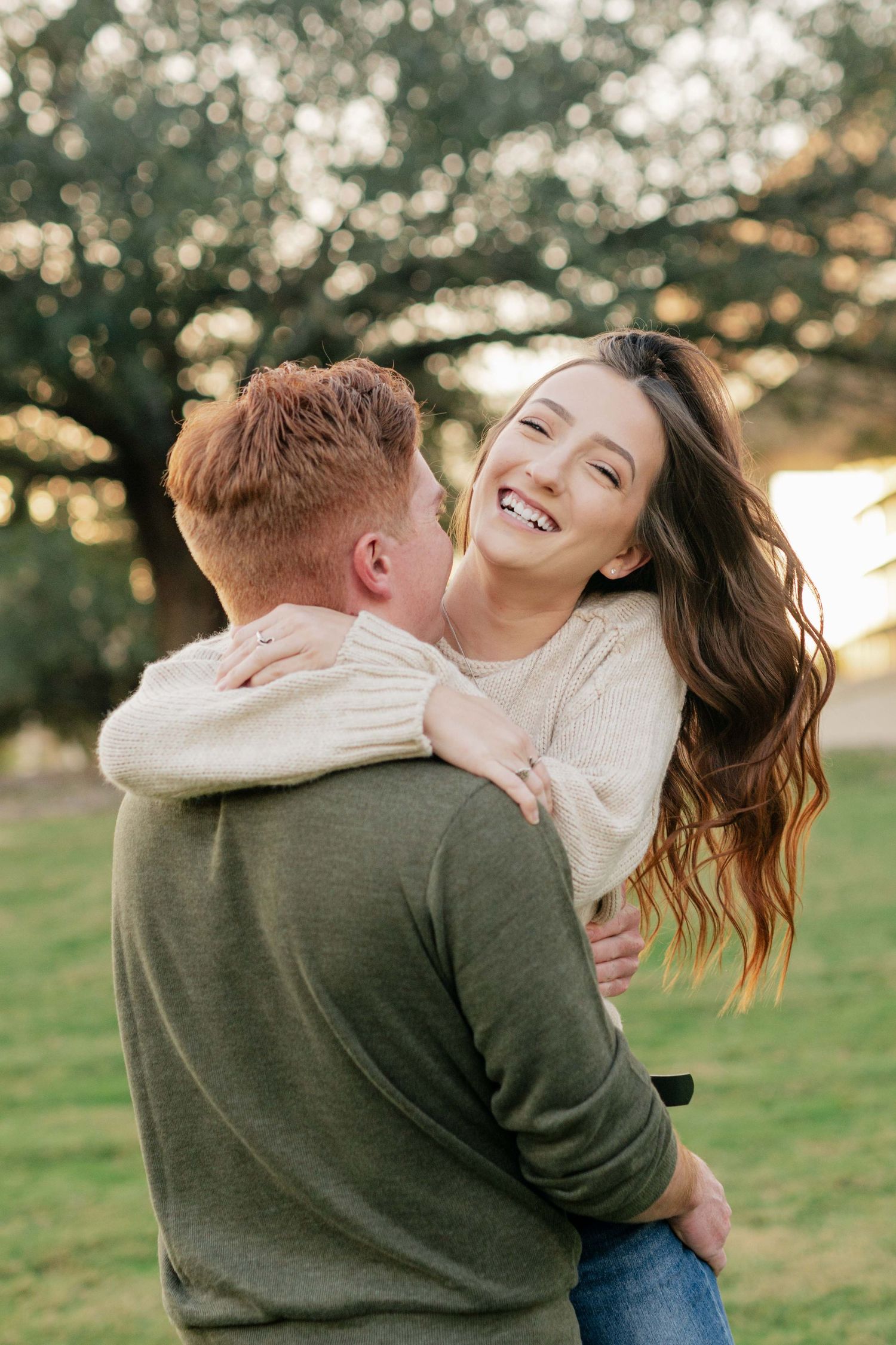 A joyful couple shares a tender moment outdoors during golden hour under autumn trees.