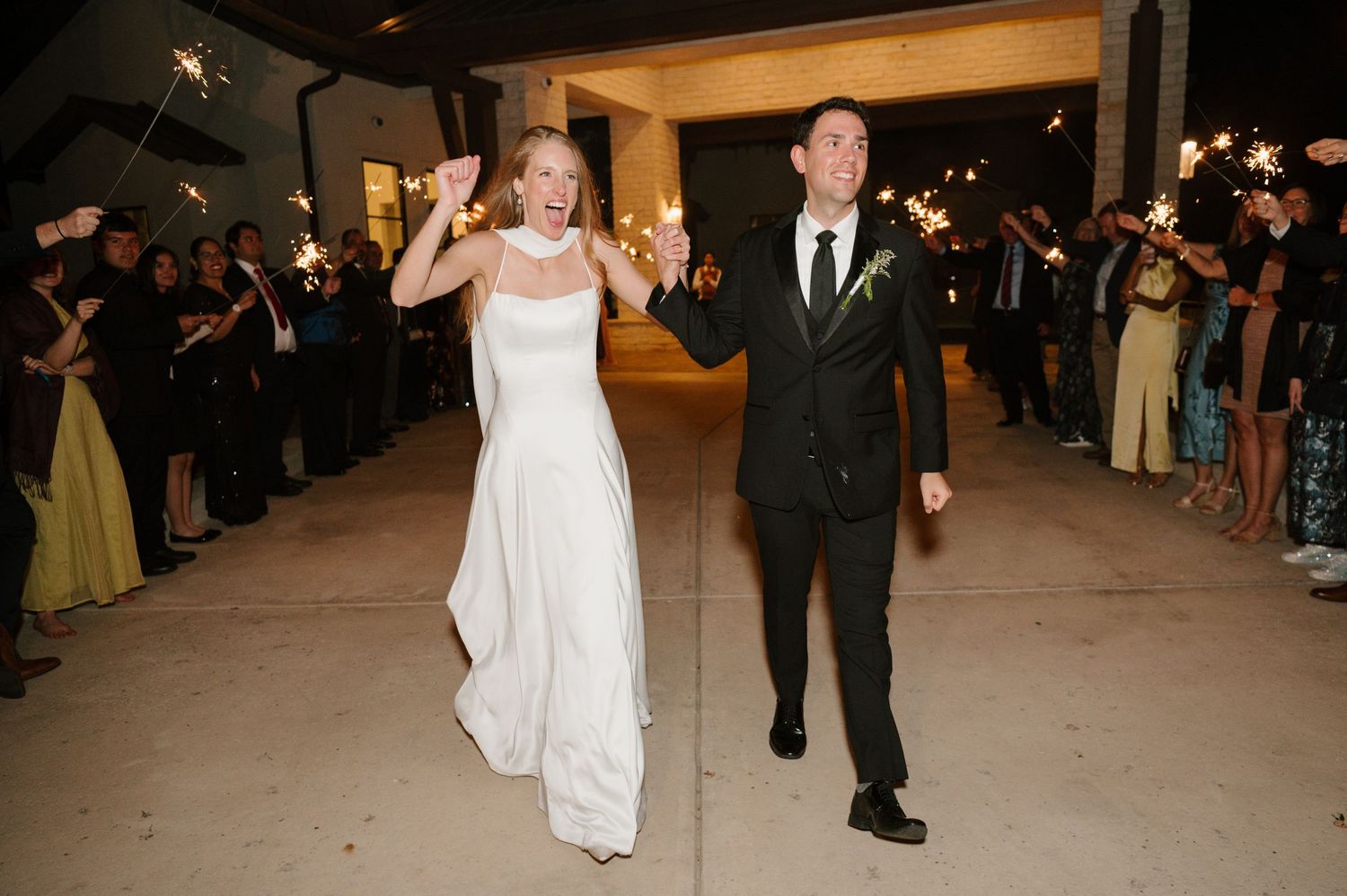 Newlyweds make their grand exit through lines of guests at evening reception.