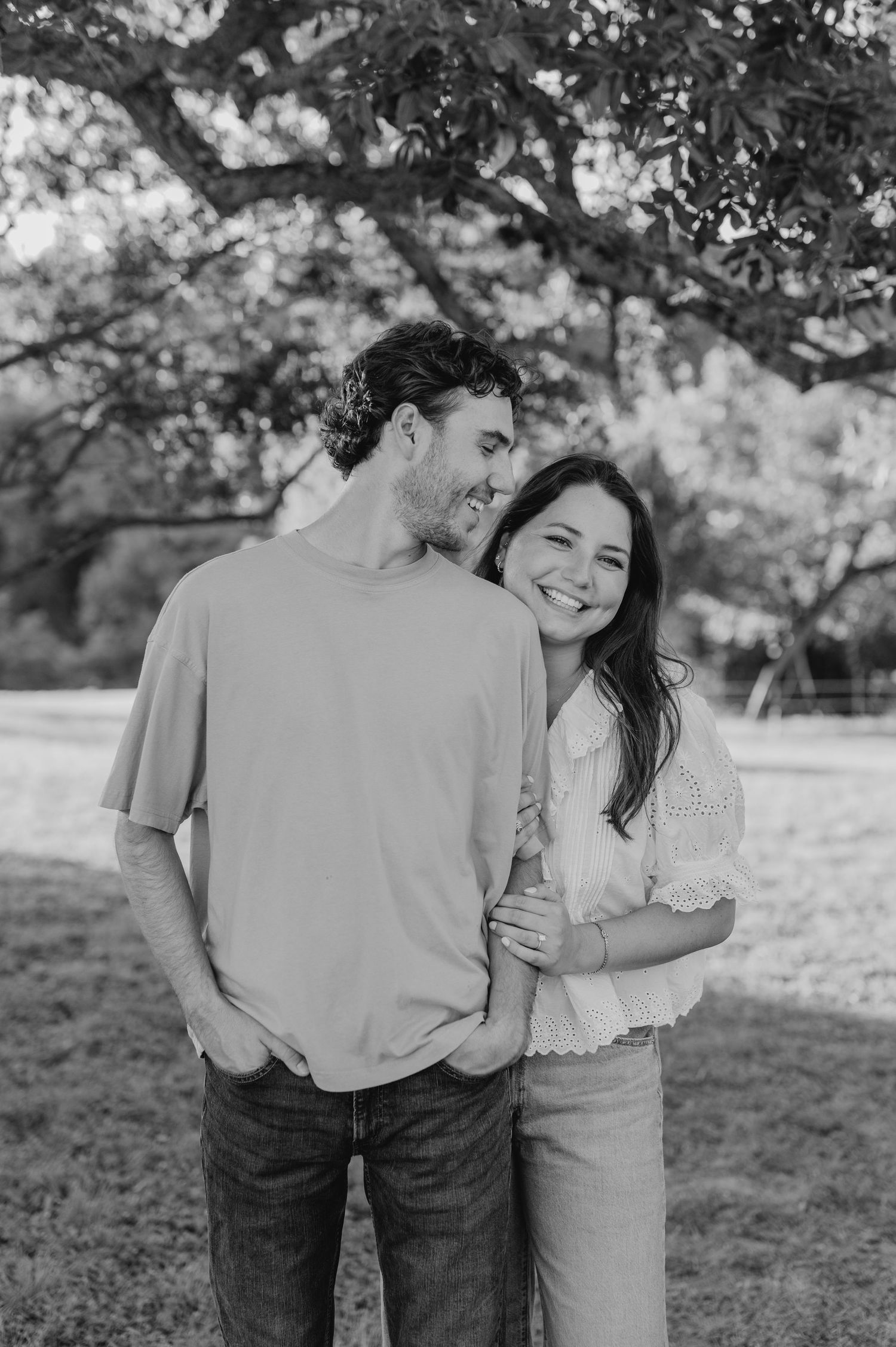 A romantic black and white photo series of a couple embracing and laughing together outdoors.