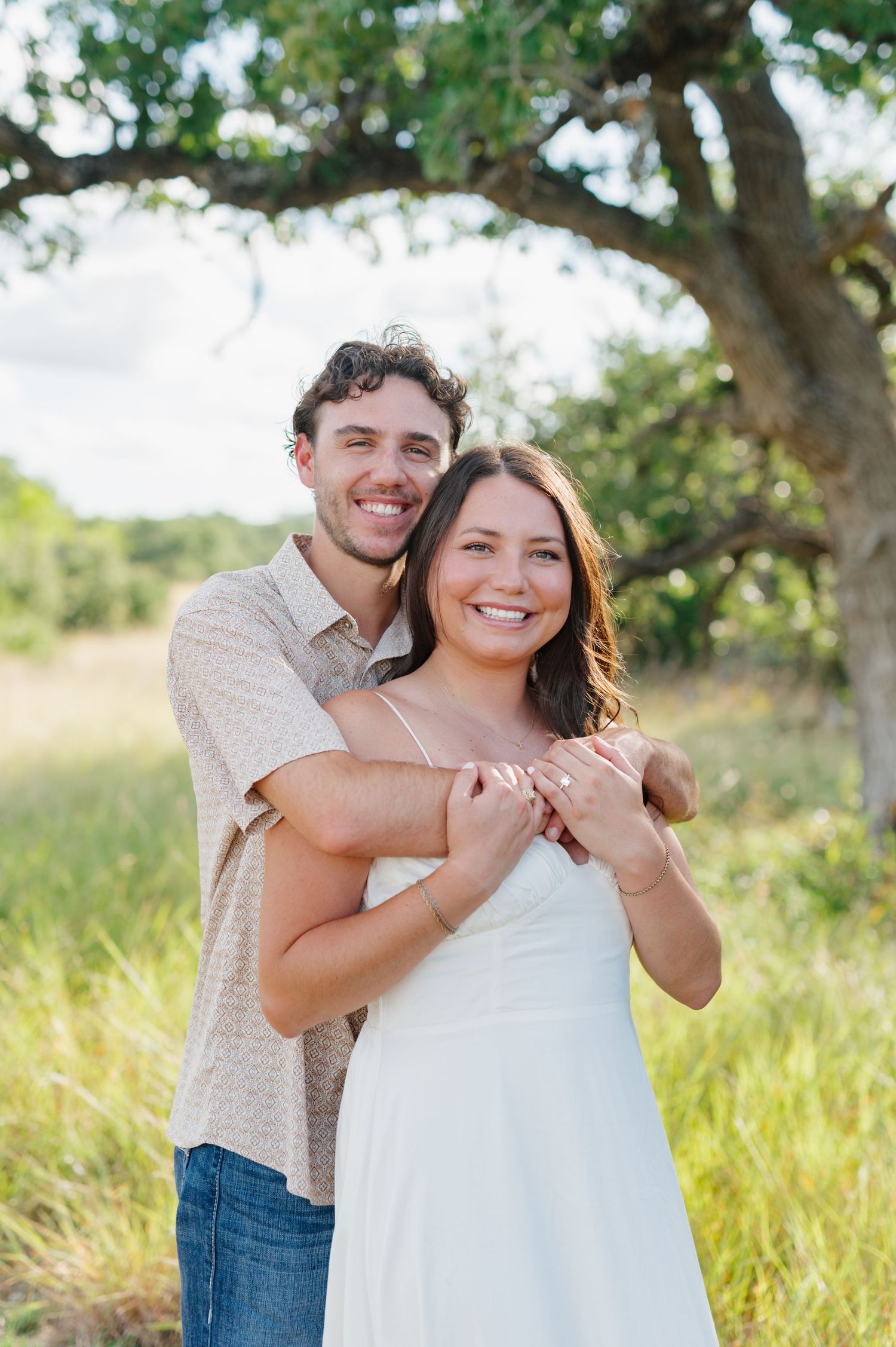 A joyful couple sharing candid moments and laughter in a sun-drenched field.
