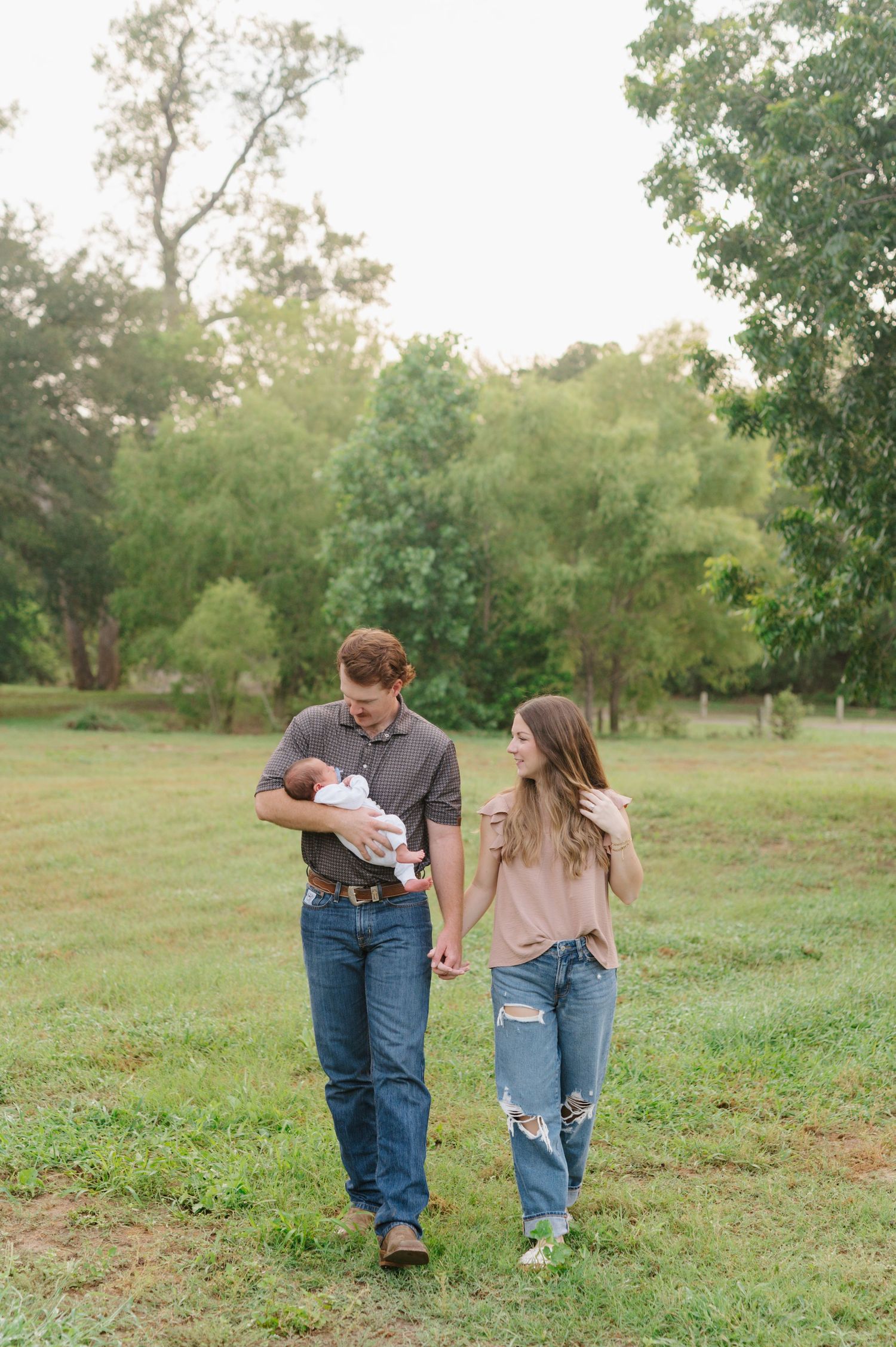 Family portrait session in a green meadow showing candid moments and interactions between loved ones.