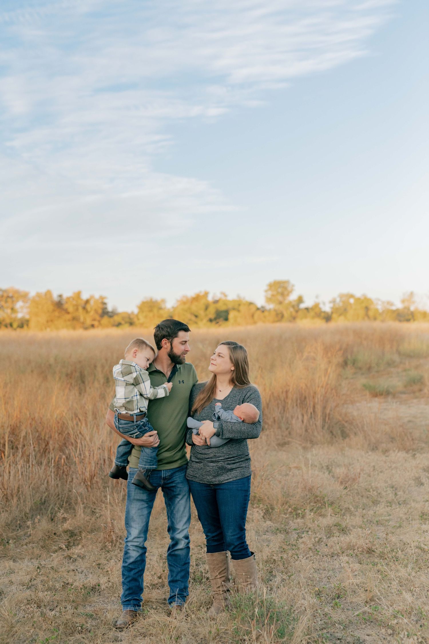 Family portrait in a golden field at sunset with small children and autumn colors.