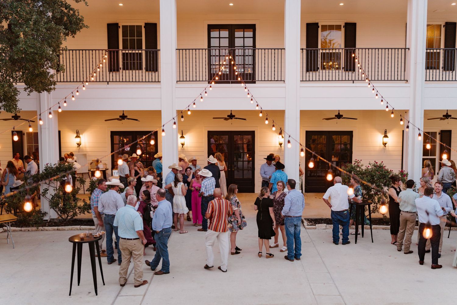Wedding guests mingling in an elegant columned reception hall with warm lighting.