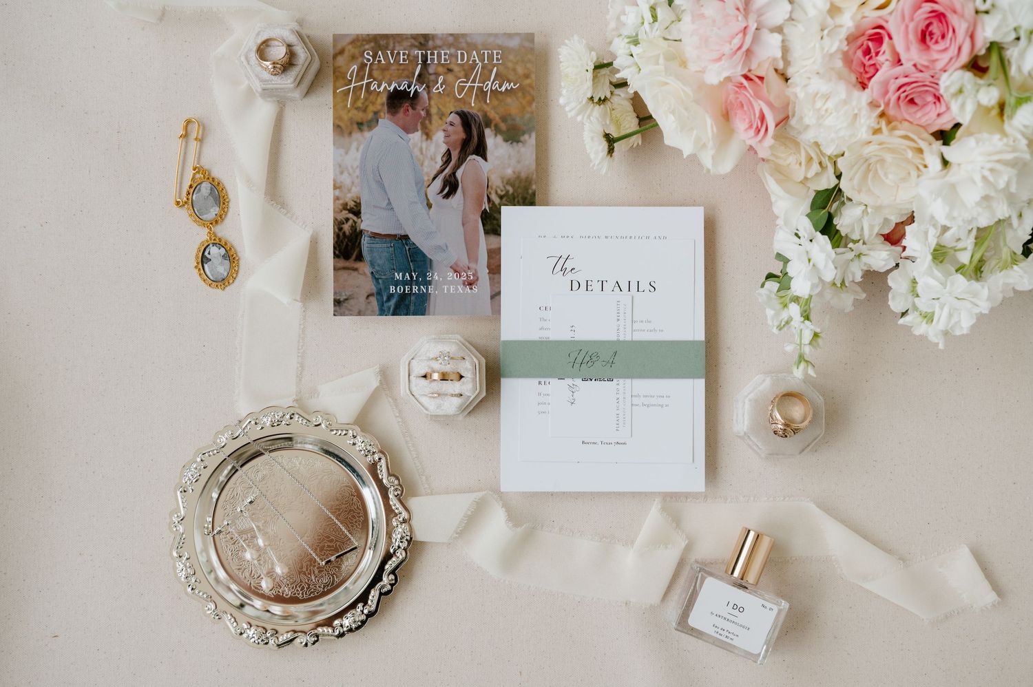 Wedding details including pink roses, floral arrangements, invitations, and vintage decorative elements laid out on beige surface.