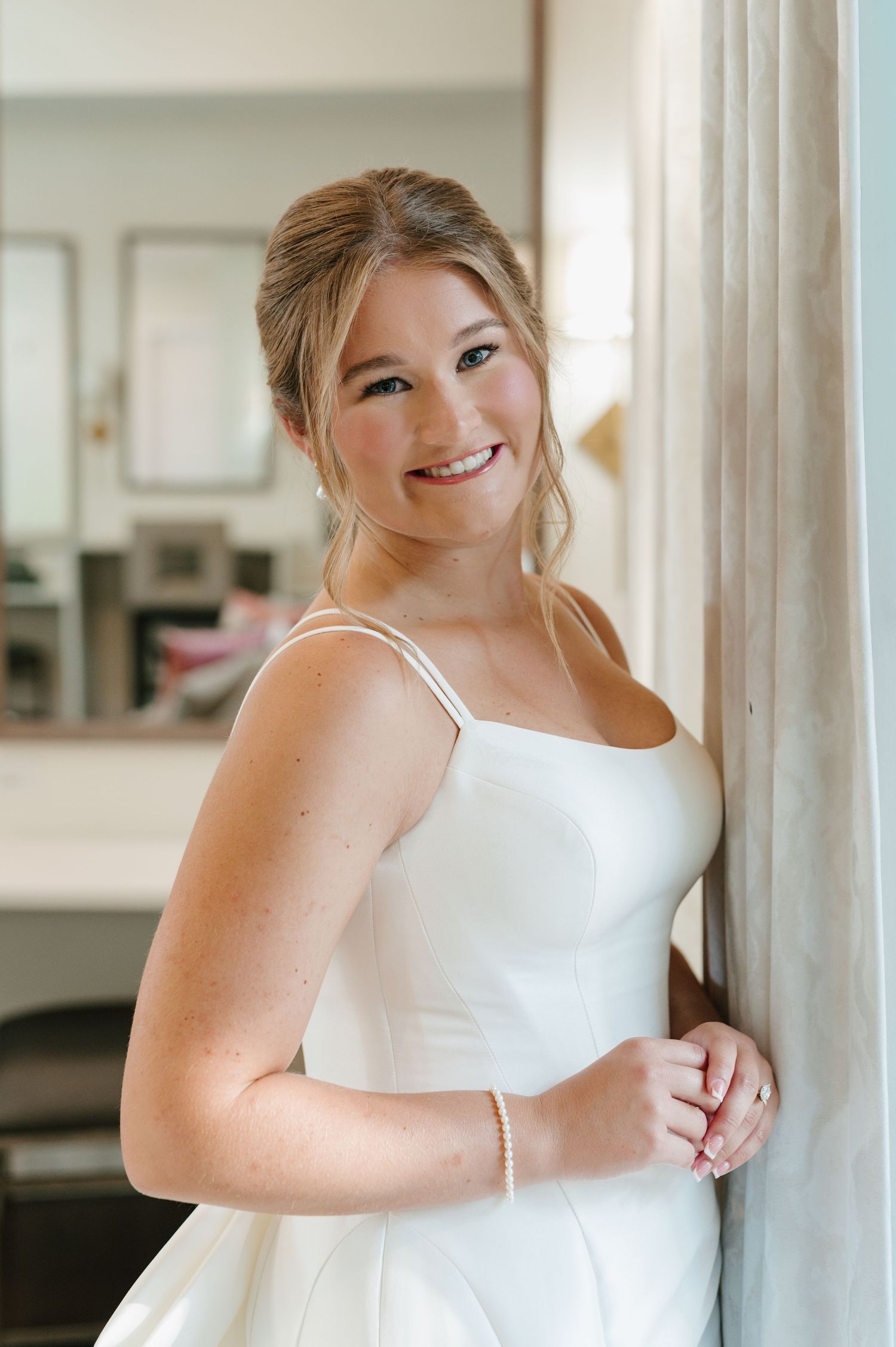 Candid bridal portrait showing joyful expression while holding white floral bouquet.
