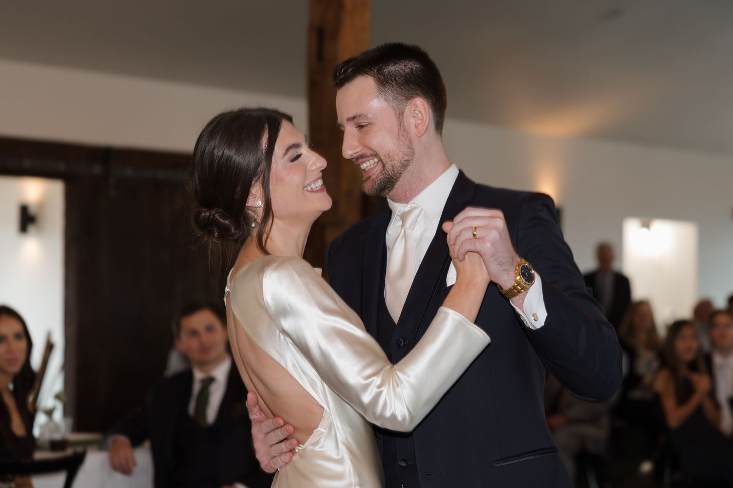 A couple dances together at an elegant wedding reception with guests watching in the background.