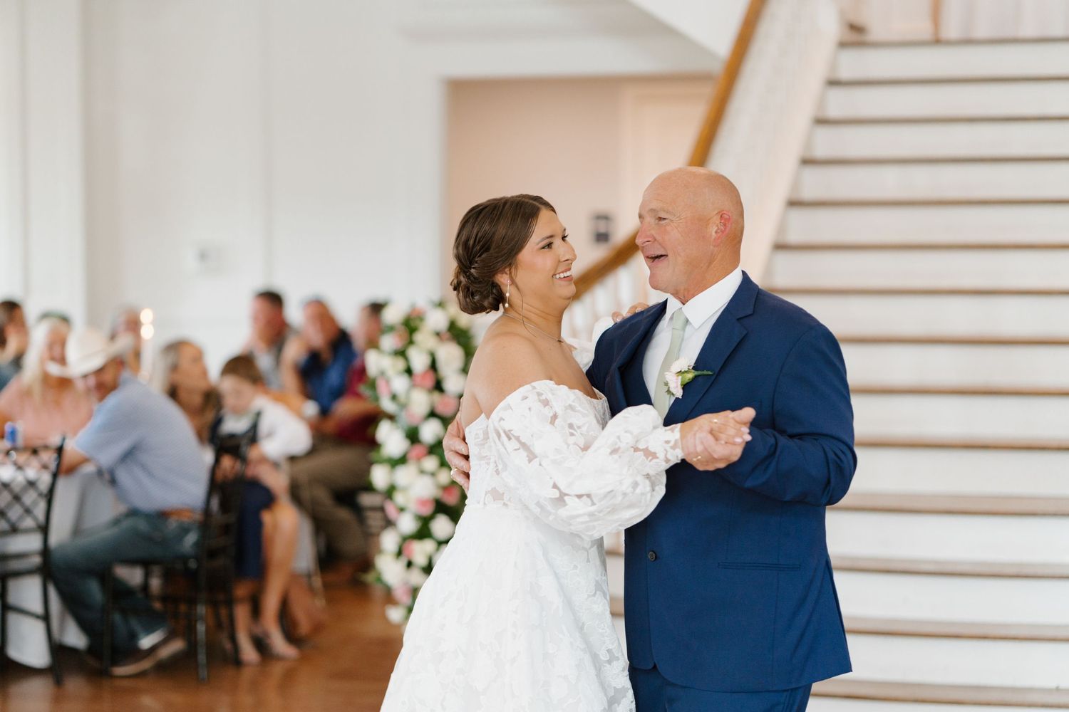 Wedding couple sharing their first dance in an elegant white reception venue.