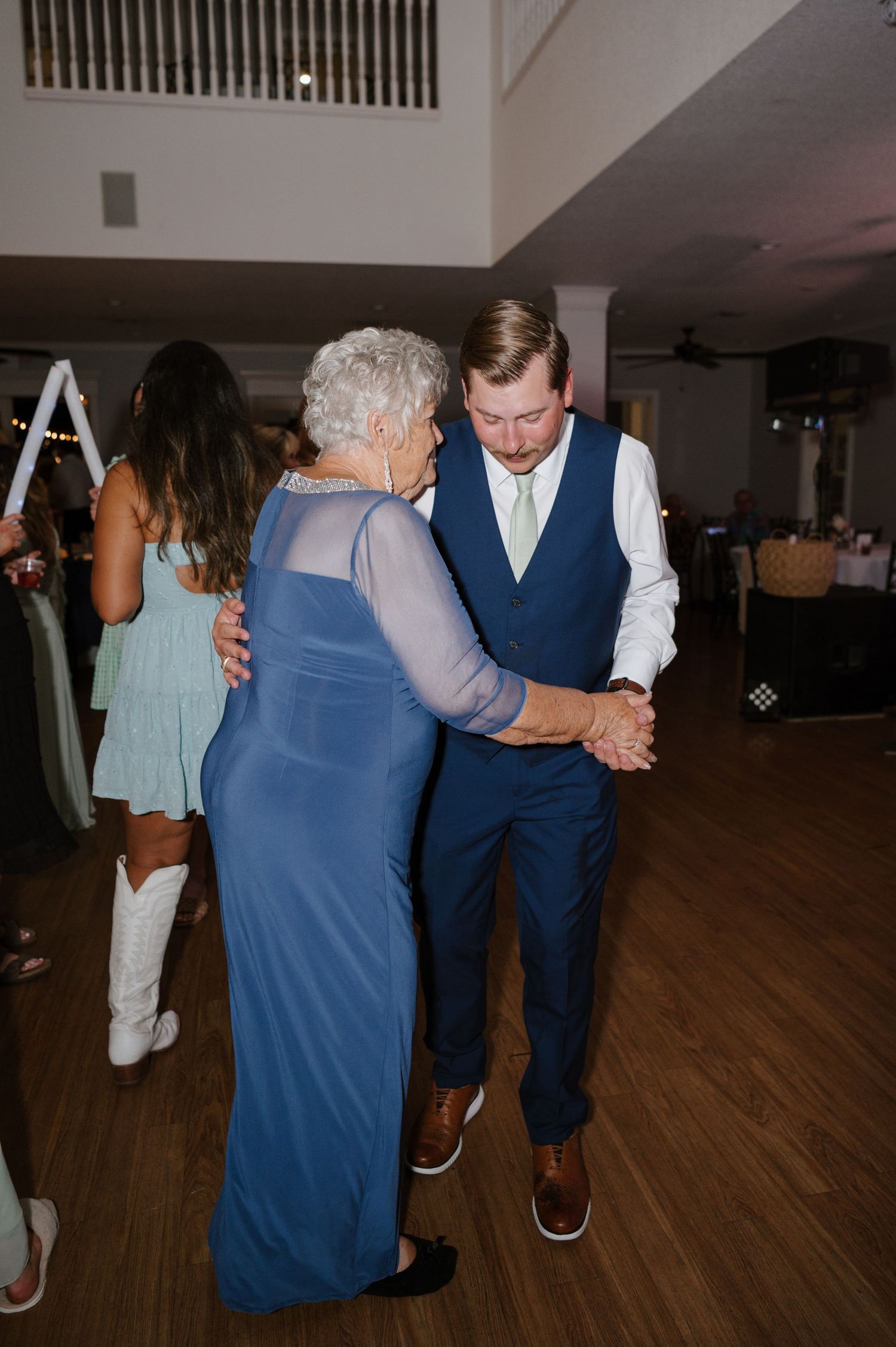People dancing together on a wooden floor at an evening reception or celebration event.