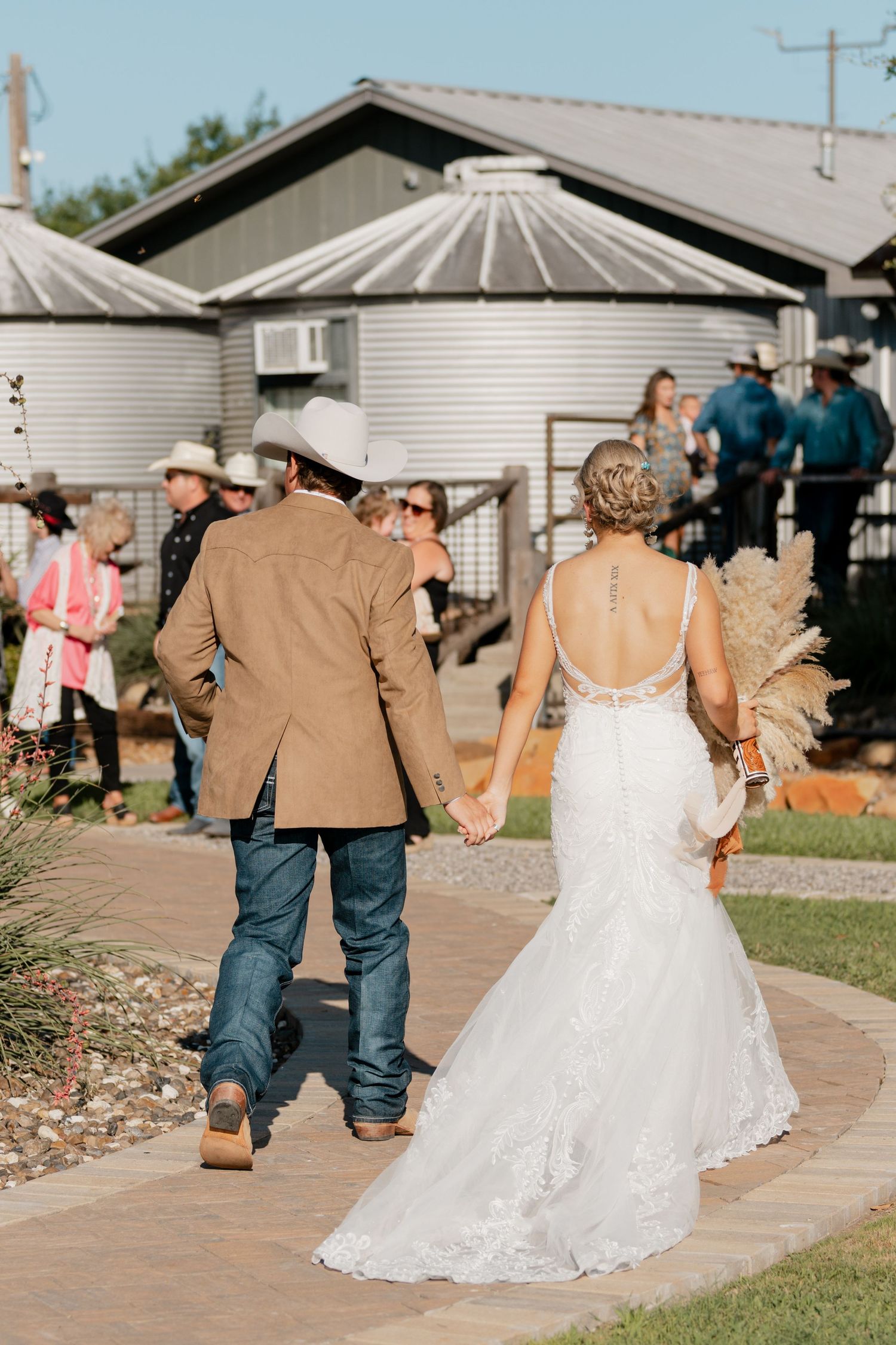 Newlyweds walking along garden path after rustic outdoor wedding ceremony.