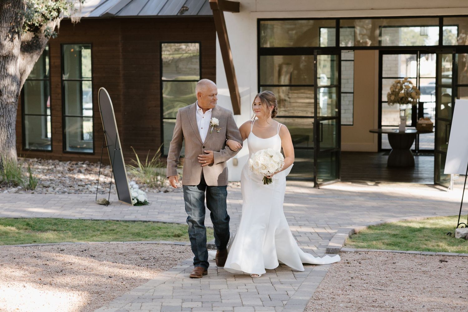 Wedding celebration outdoors near rustic building with stone pathway.