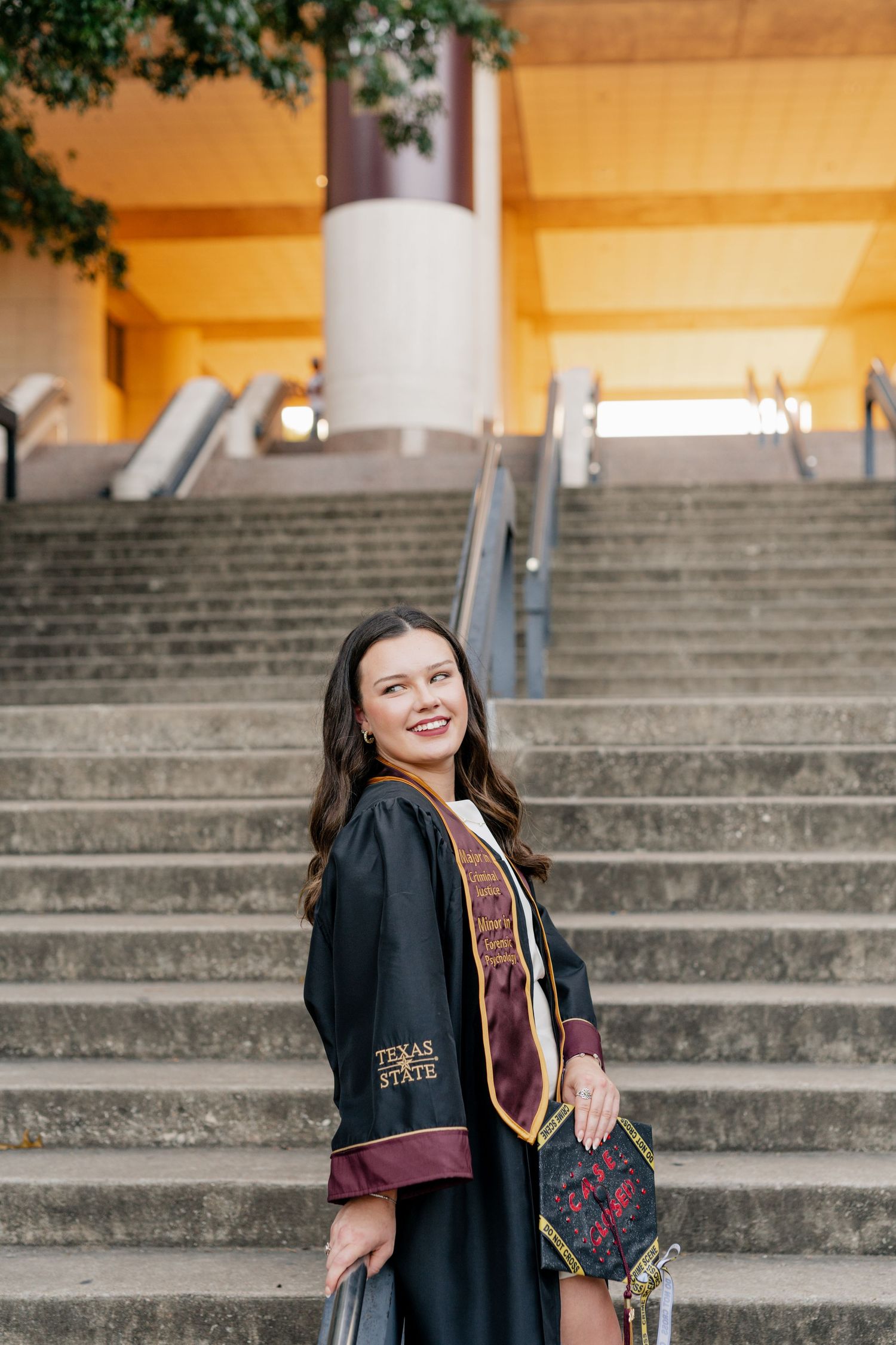 A girl's senior session at Texas State University in front of the library staircase.