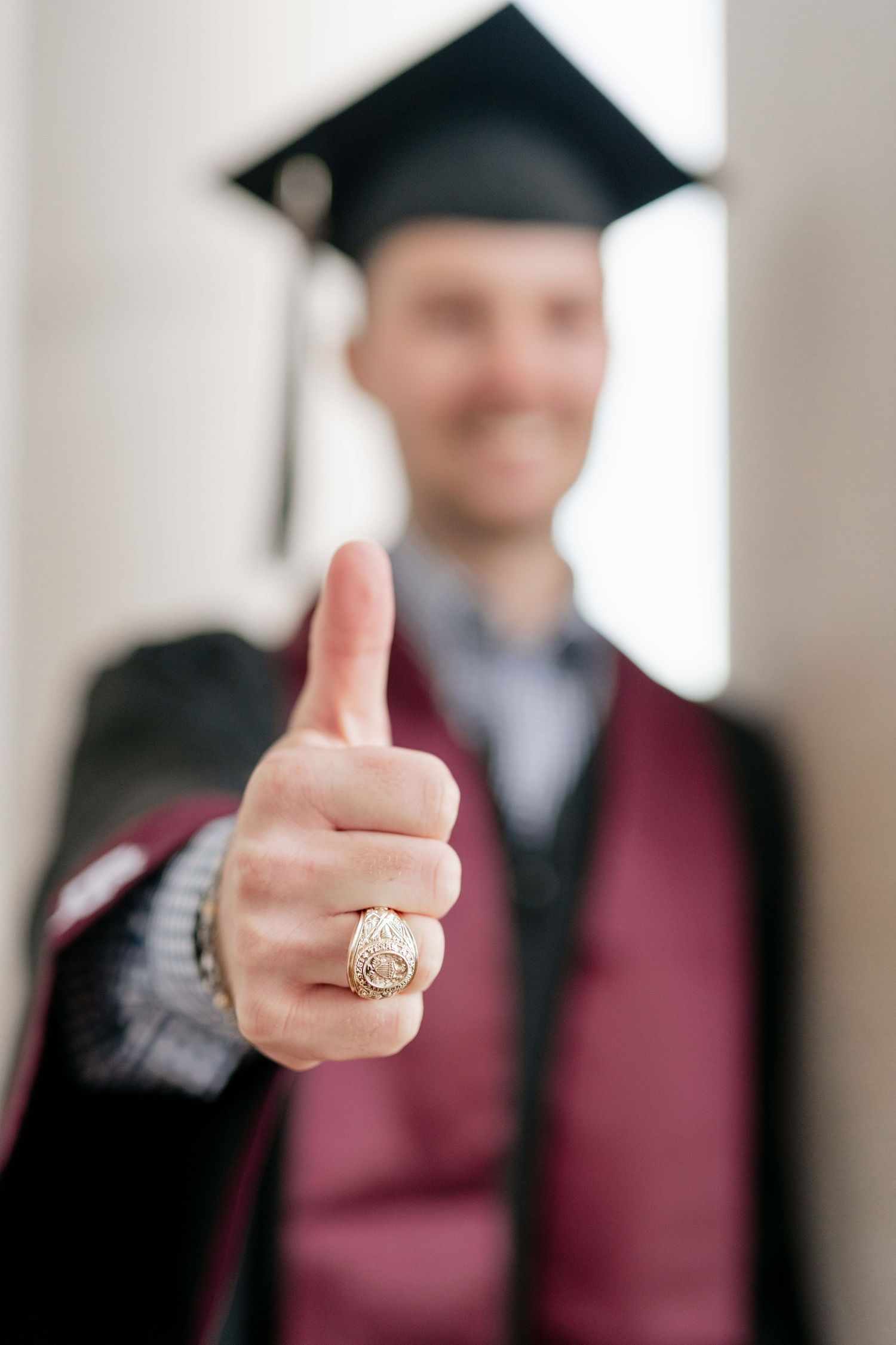 Close up of graduate's hand showing class ring with thumbs up gesture.
