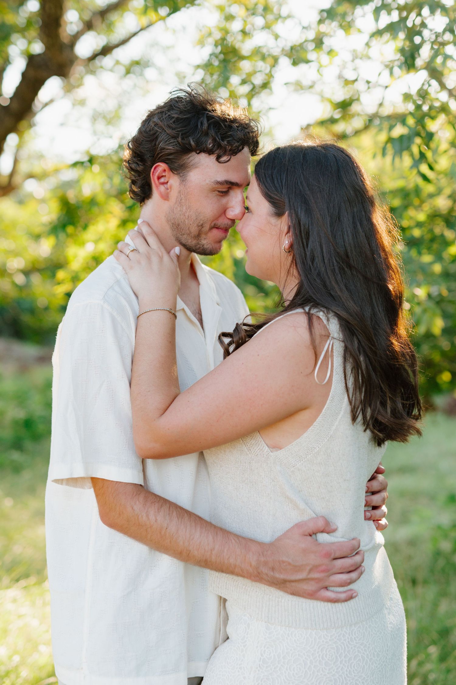 Intimate couple's portrait session with soft natural lighting and green foliage backdrop.