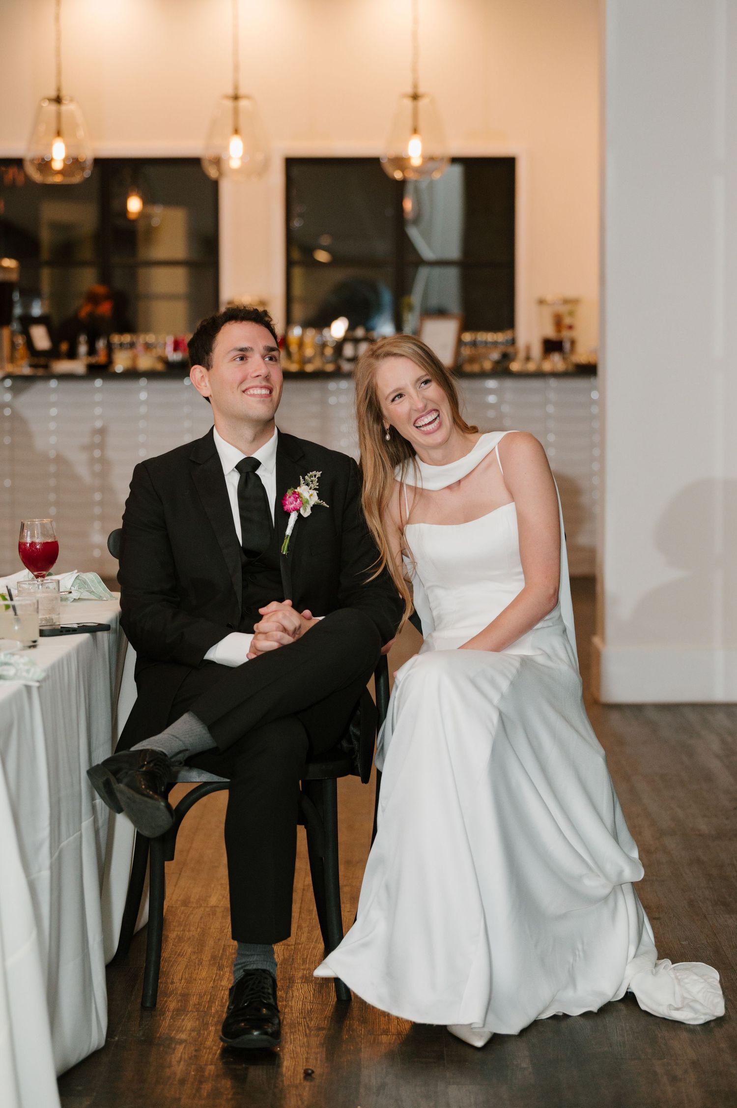 Couple sharing joyful moment in elegant reception venue with warm lighting.