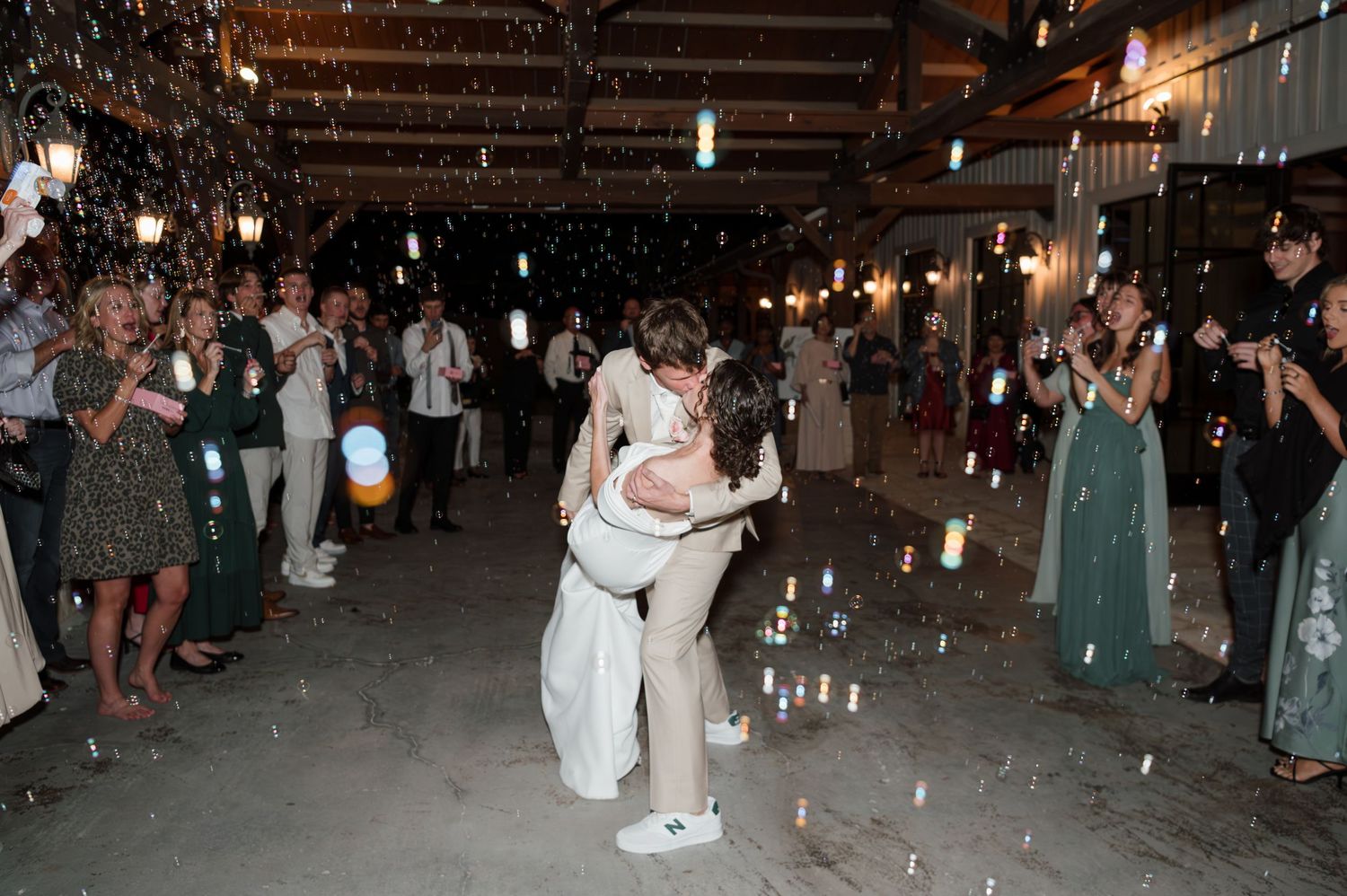 Couple shares romantic dance surrounded by guests and candlelight at wedding reception.