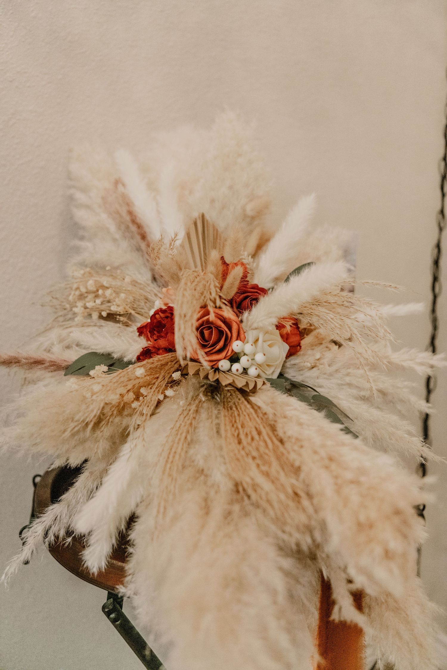 A bohemian-style dried pampas grass and rose wedding bouquet in neutral beige and coral tones.